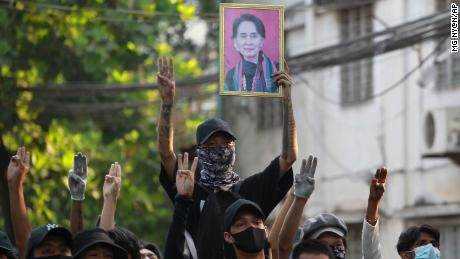 Anti-Putsch-Demonstranten erheben die drei Finger des Widerstands und ein Porträt des abgesetzten Führers Aung San Suu Kyi, um sich bei einem Protest in der Gemeinde Tarmwe in Yangon am 1. April auf die Konfrontation mit der Polizei vorzubereiten.
