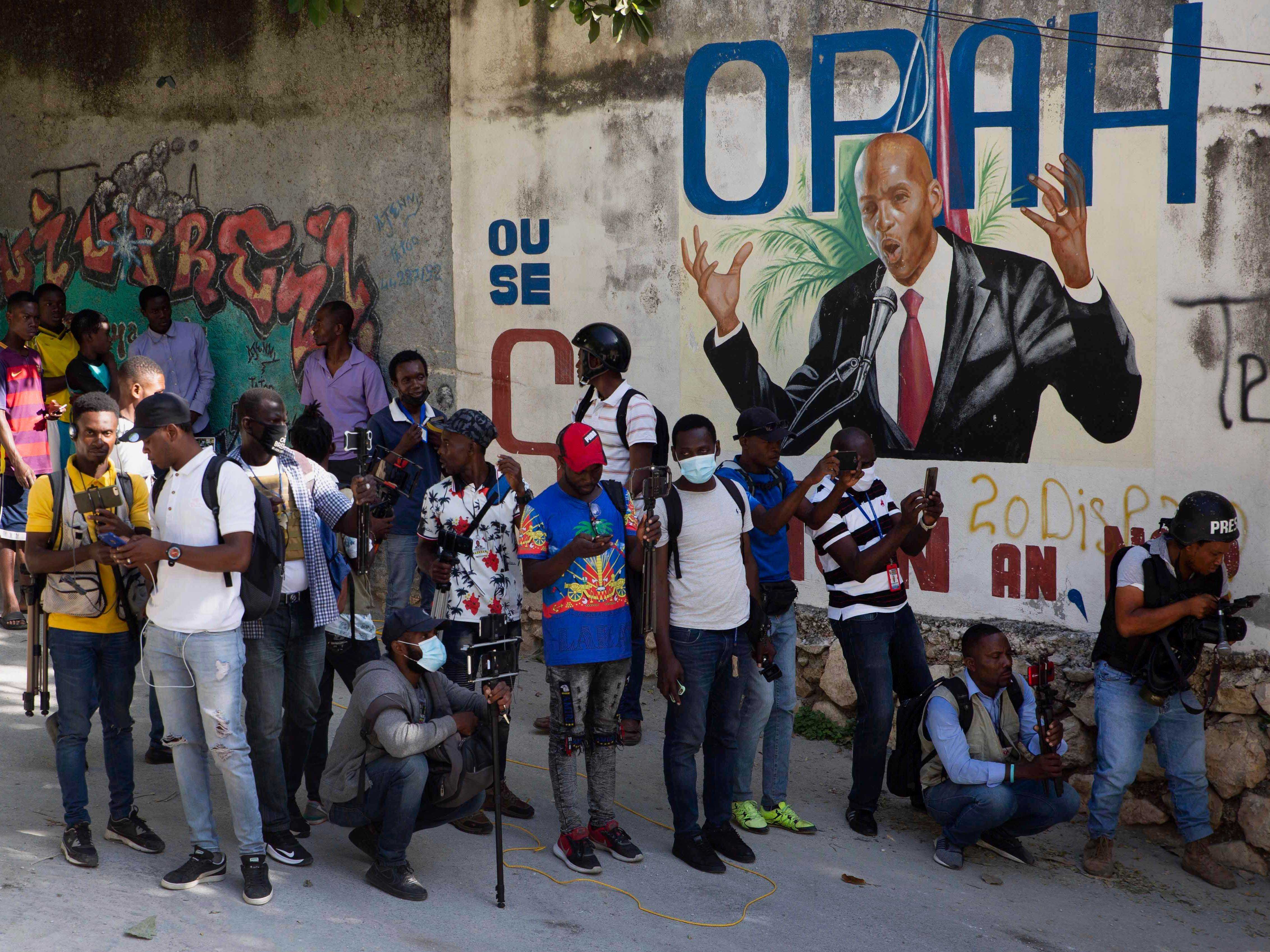 Journalisten versammeln sich in der Nähe eines Wandgemäldes mit dem haitianischen Präsidenten Jovenel Moise in Haiti