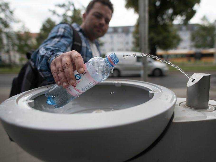 Ein Mann füllt eine Wasserflasche an einem Trinkbrunnen