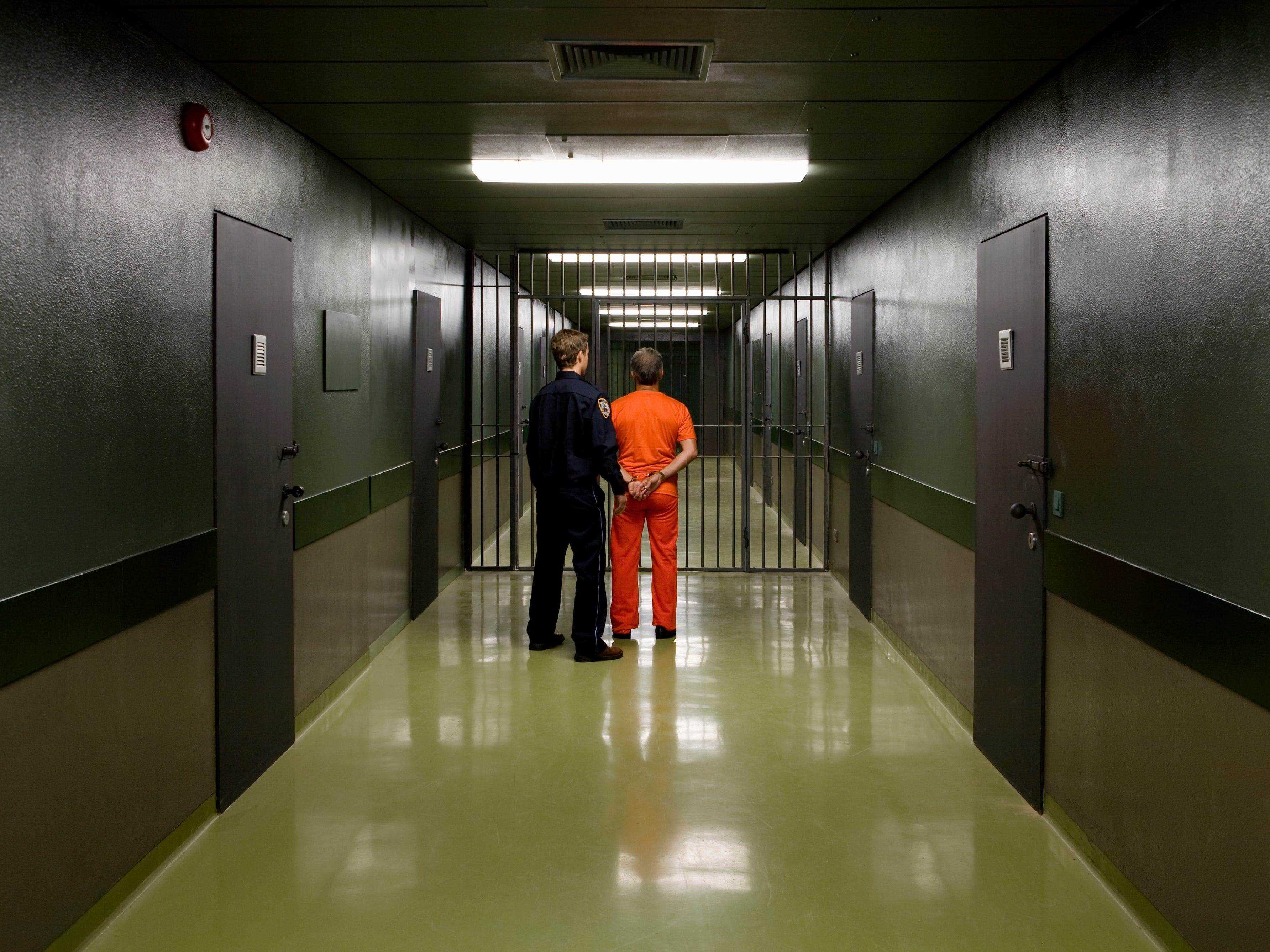Ein Gefängniswärter führt einen Gefangenen durch einen Korridor