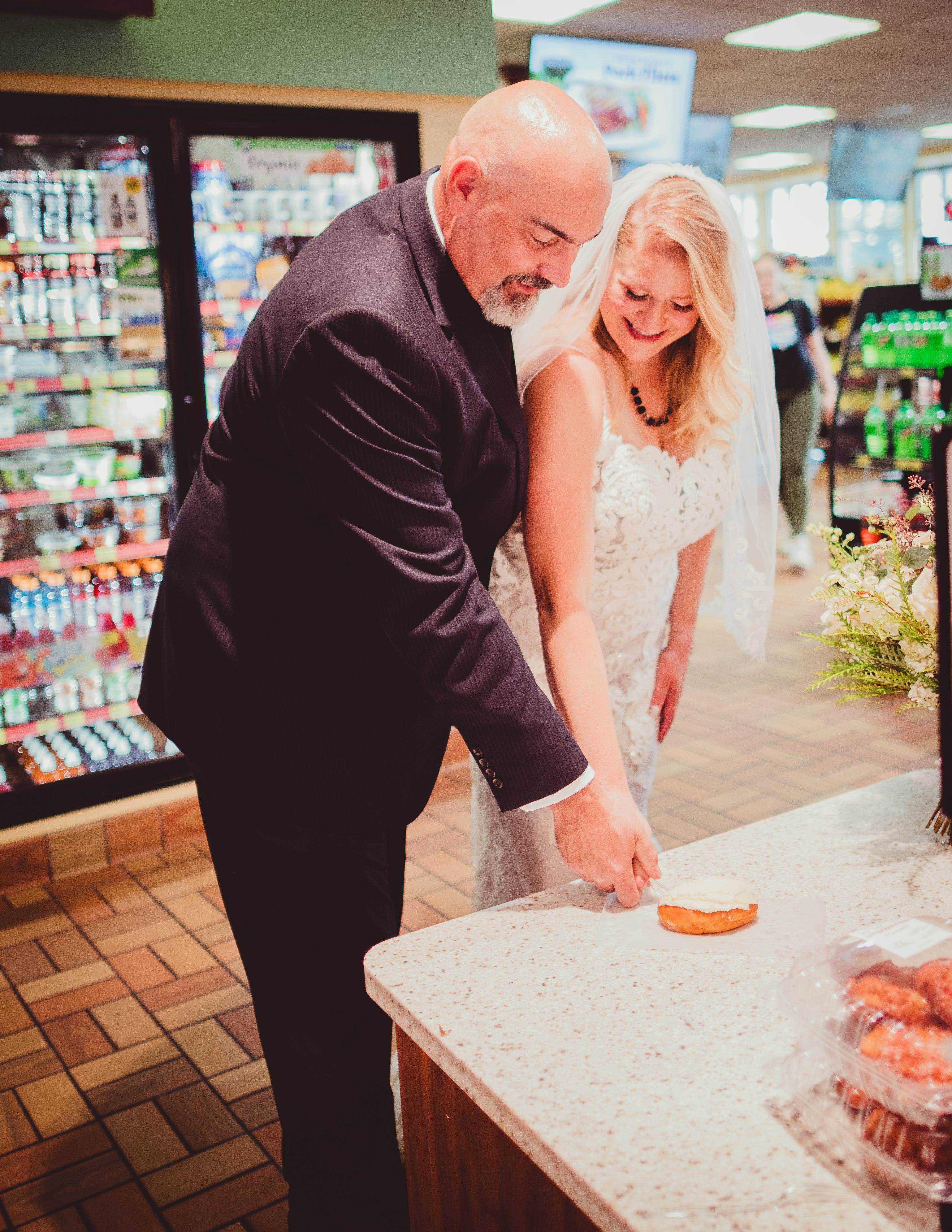 Ein Brautpaar schneidet an einer Tankstelle einen Donut.
