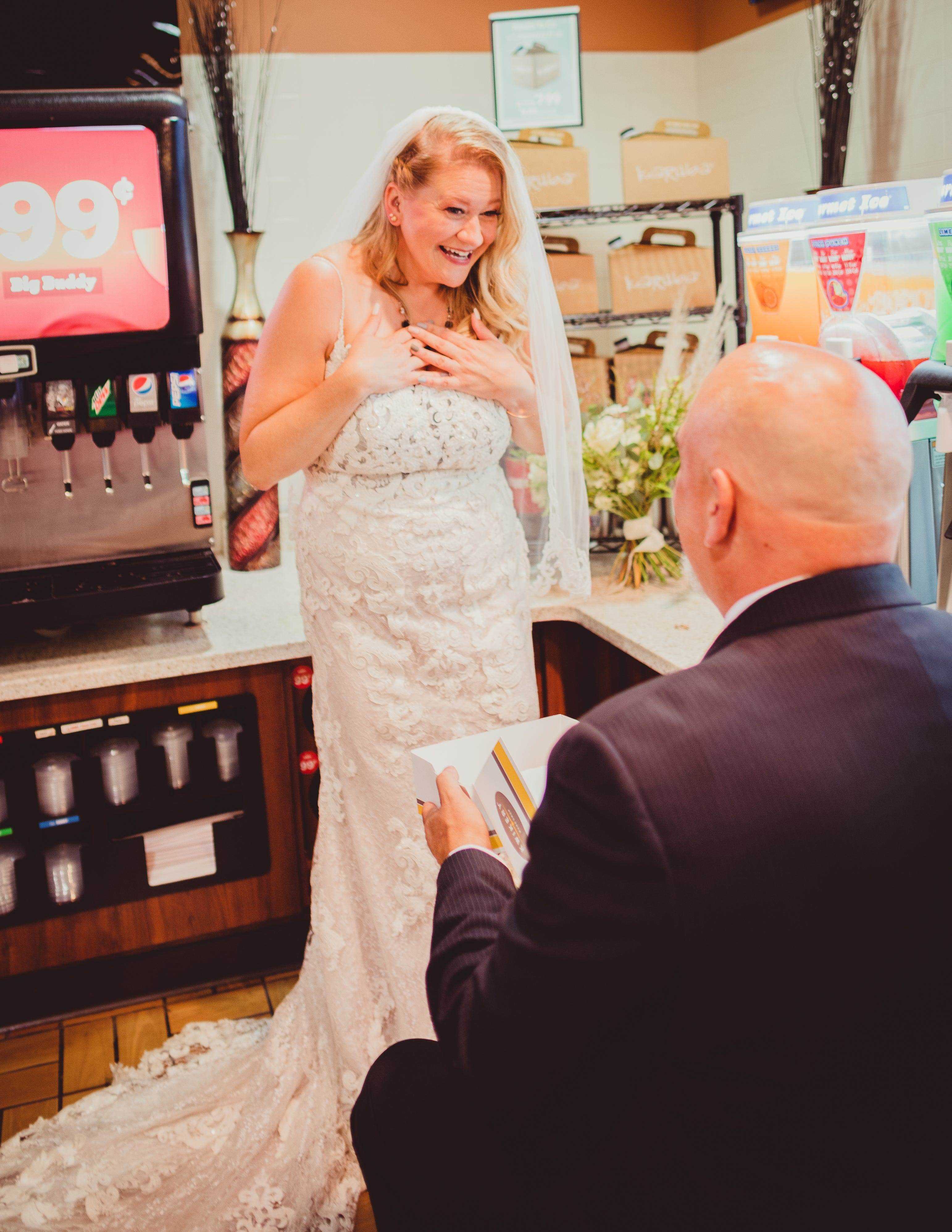Ein Bräutigam kniet an einer Tankstelle vor einer Braut.