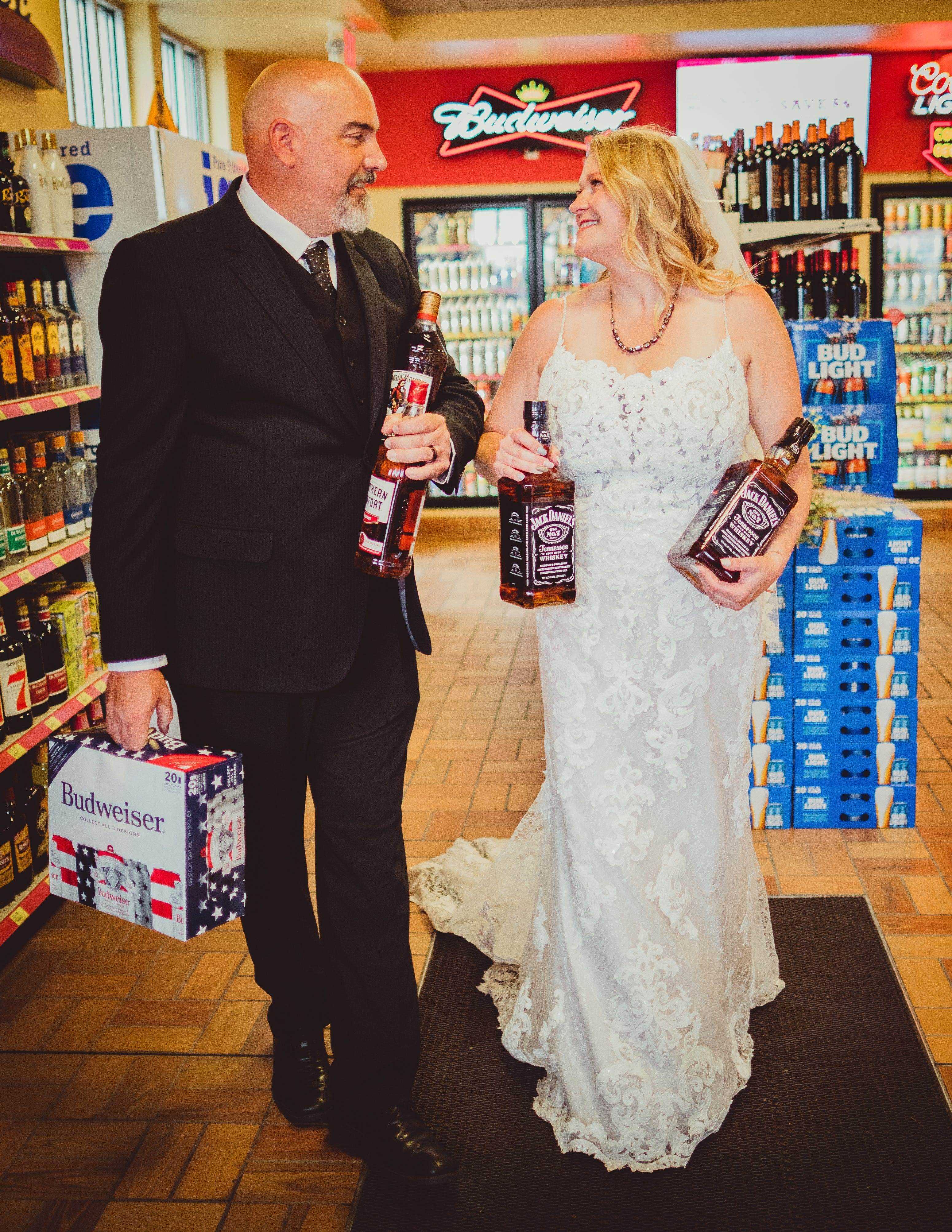 Eine Braut und ein Bräutigam halten Flaschen Whisky und Bier.