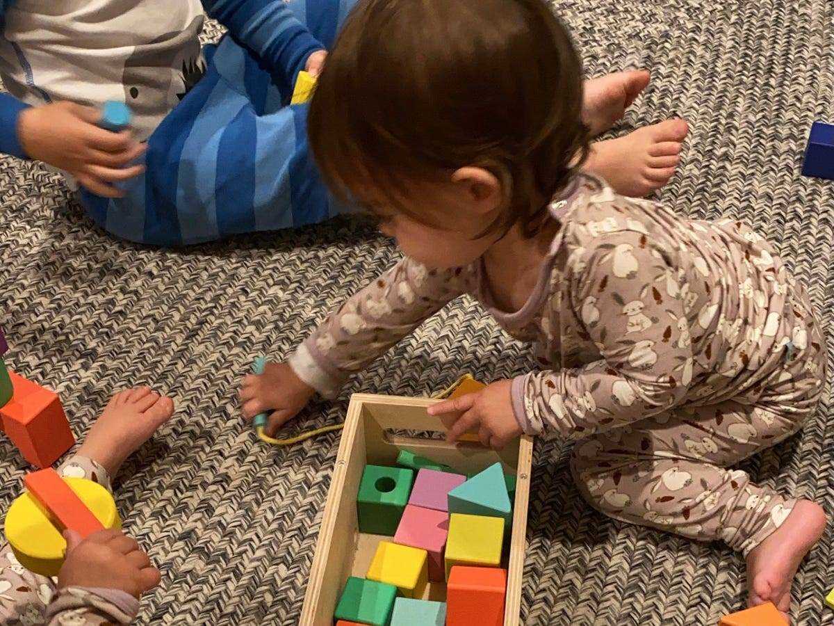 zwei Kleinkinder spielen mit bunten Bausteinen