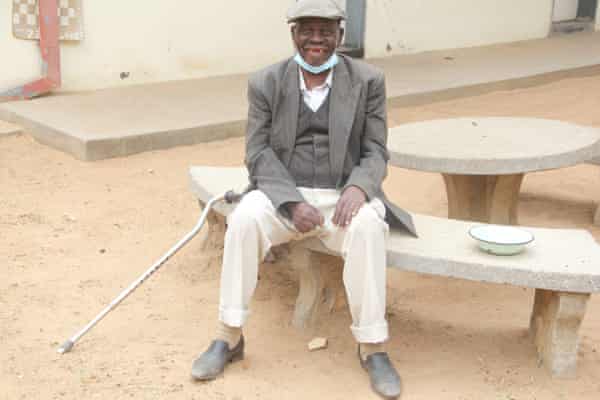 Domingo Zakani sitzt in einem Innenhof von Soda in Harare.  Er lebt seit fünf Jahren im Haus.