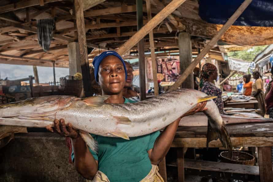 Frau Abdullahi hält einen großen 'Barakuta'-Fisch.  Sie folgte ihrer Mutter in die Arbeit auf dem Markt