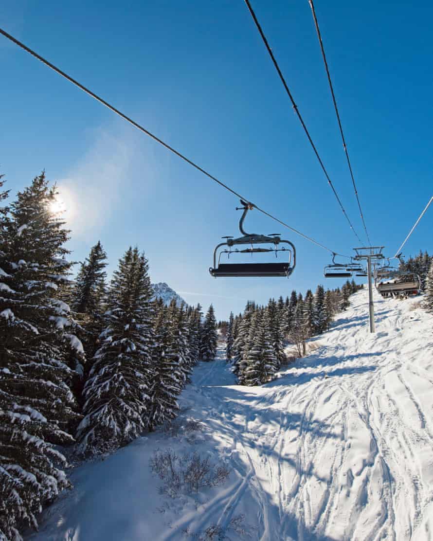 Mit dem Sessellift einen alpinen Berghang hinauffahrenPanoramablick auf eine schneebedeckte alpine Bergkette während der Fahrt mit dem Sessellift-Skilift im Sonnenlicht