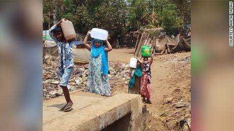 Einwohner, die 2021 Kartons mit Wasser zum Slum Ambedkar Nagar in Mumbai, Indien, tragen.