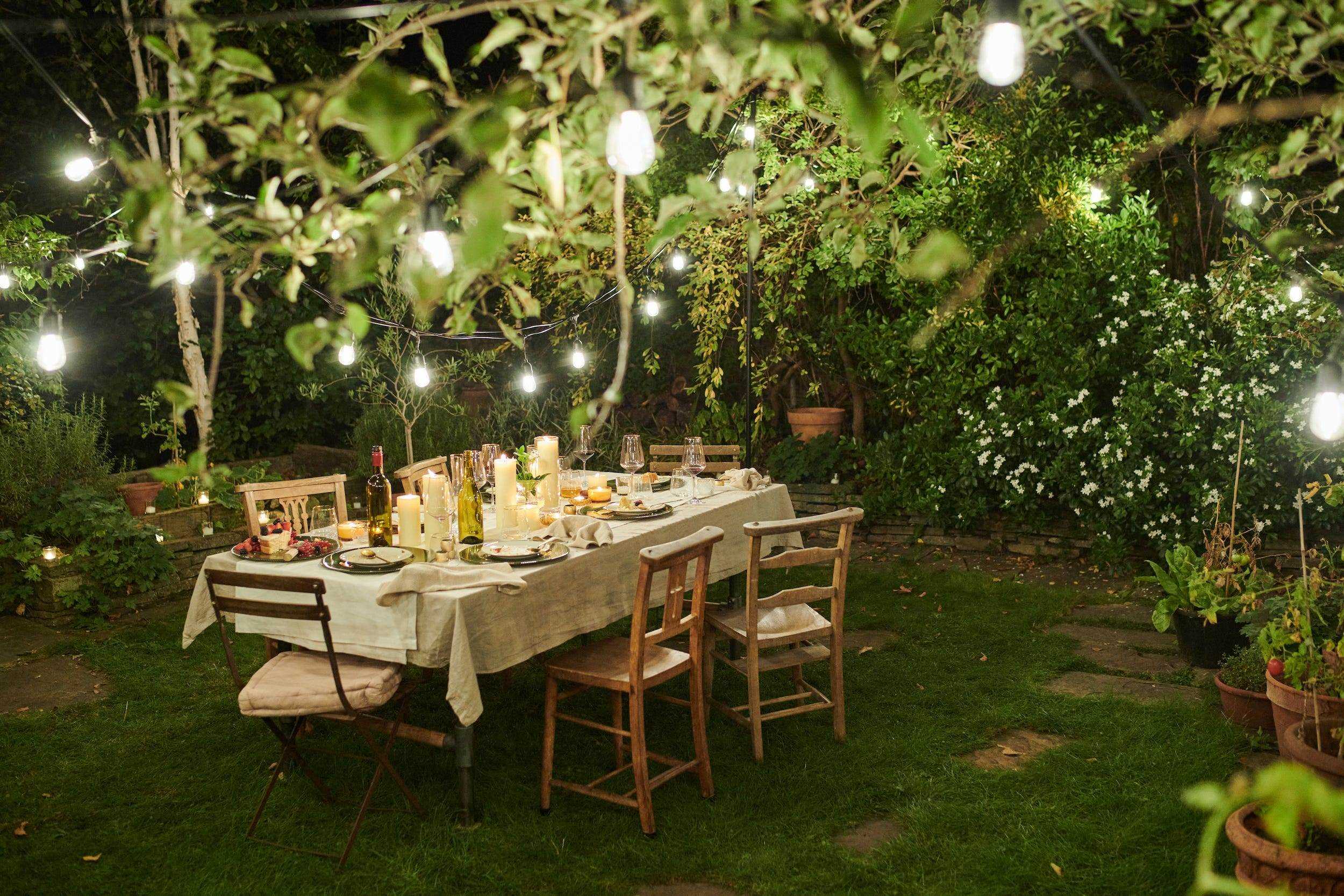 Hinterhofgarten mit Tisch, der nachts mit Lichterketten beleuchtet ist