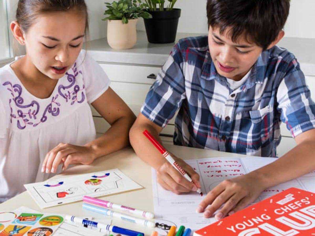 Zwei Kinder arbeiten an einer Aktivität, die in der amerikanischen Testküche enthalten ist Junge Köche Kit Ein cooles Geschenk für 8-jährige Jungen