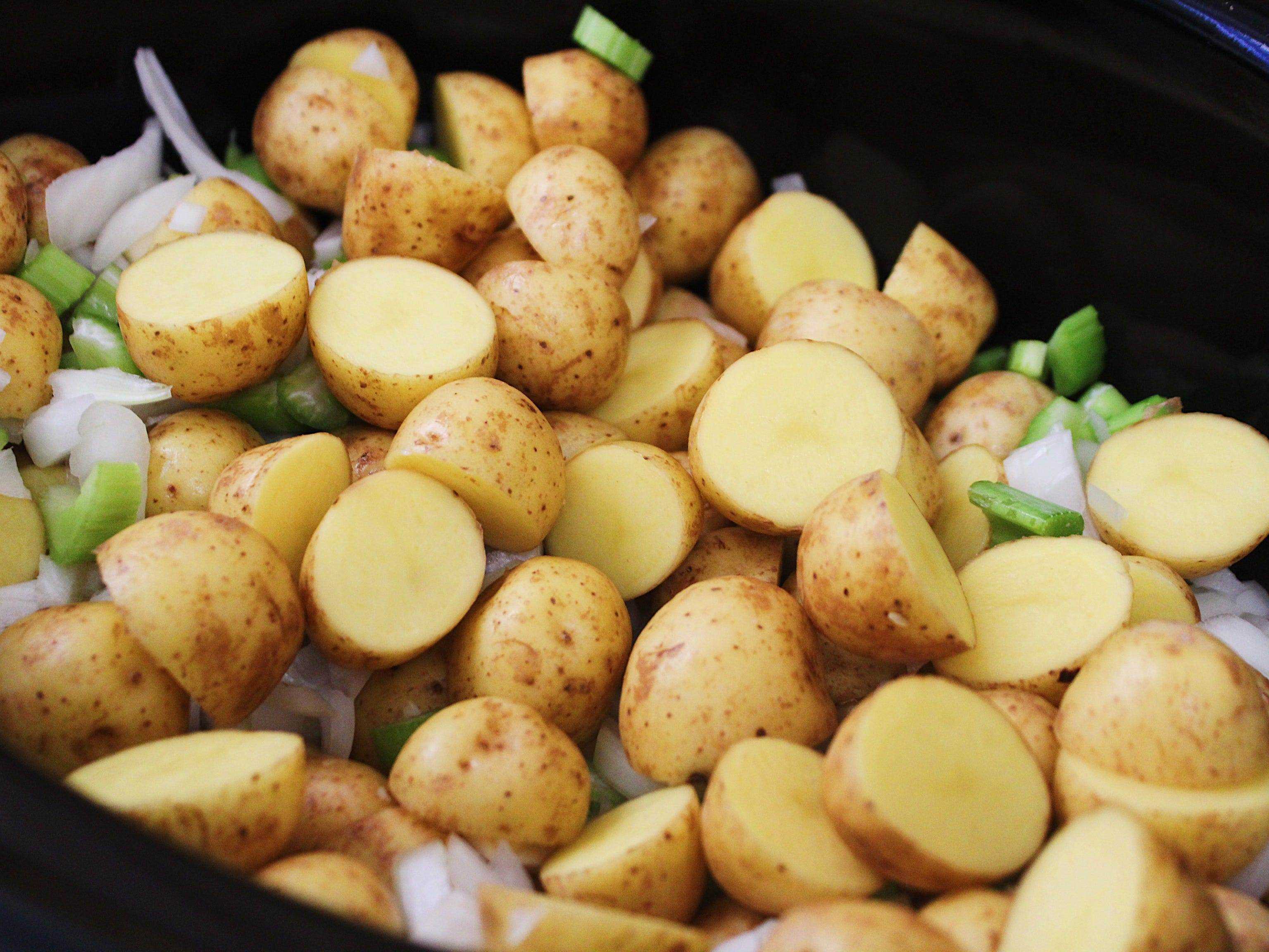 gehackte Kartoffeln, Sellerie und Zwiebeln in einem schwarzen Slow Cooker