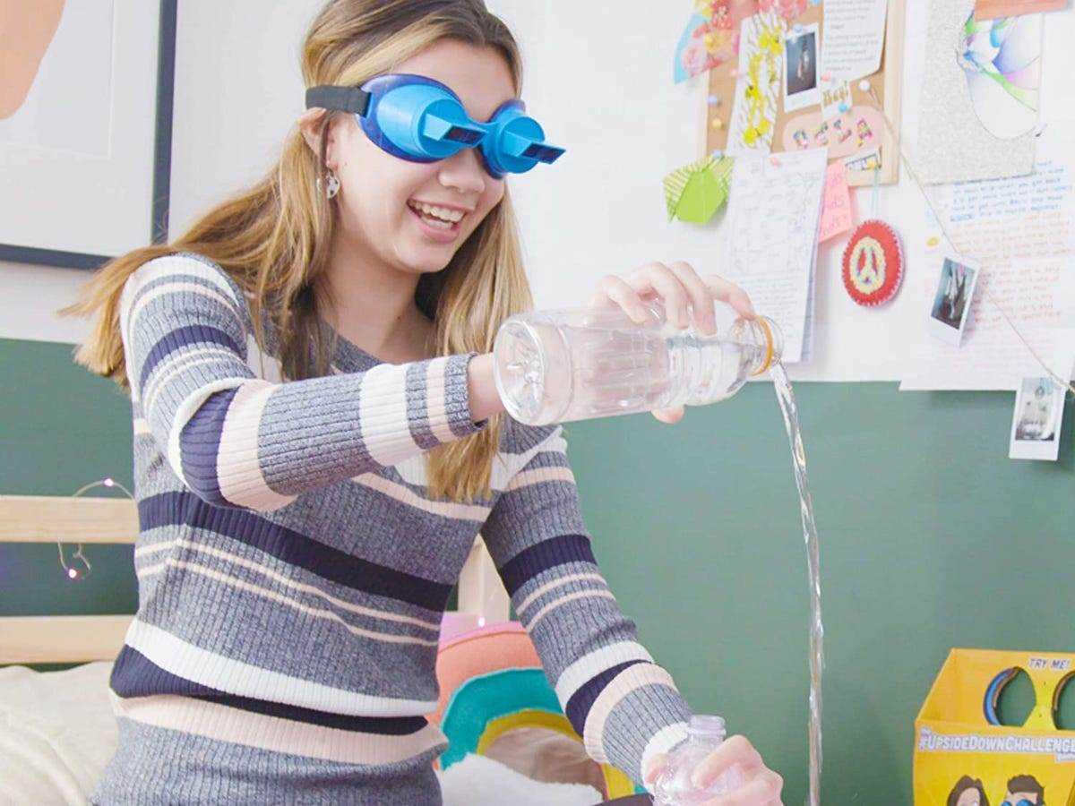 Mädchen, das eine Flasche Wasser ausgießt, während sie eine Schutzbrille aus dem Upside-Down-Spiel trägt
