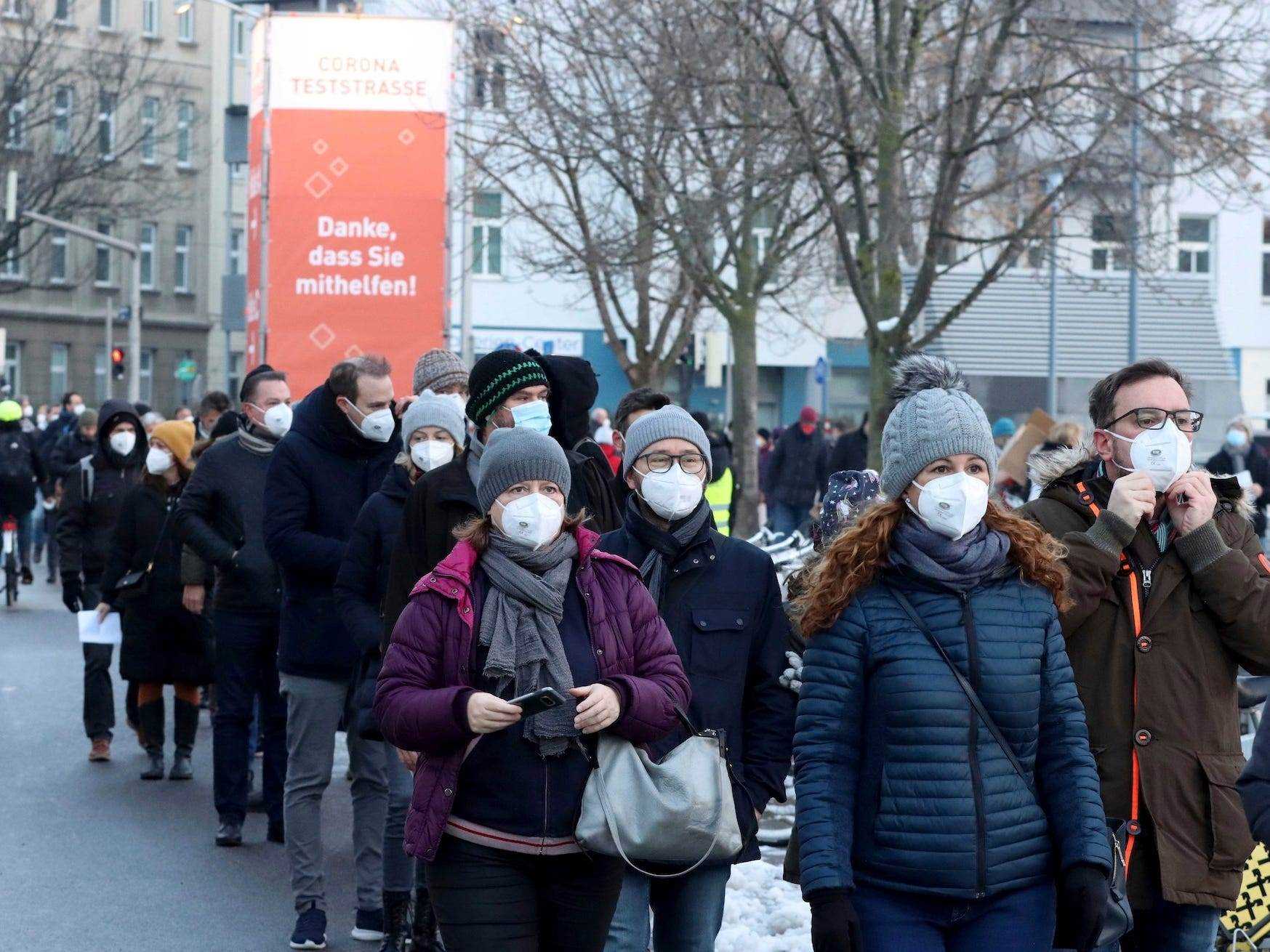 Menschen mit Masken stehen in Österreich Schlange