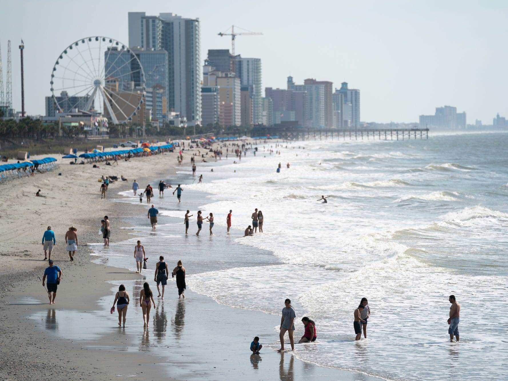 Menschen gehen am Morgen des 29. Mai 2021 in Myrtle Beach, South Carolina, am Strand entlang.