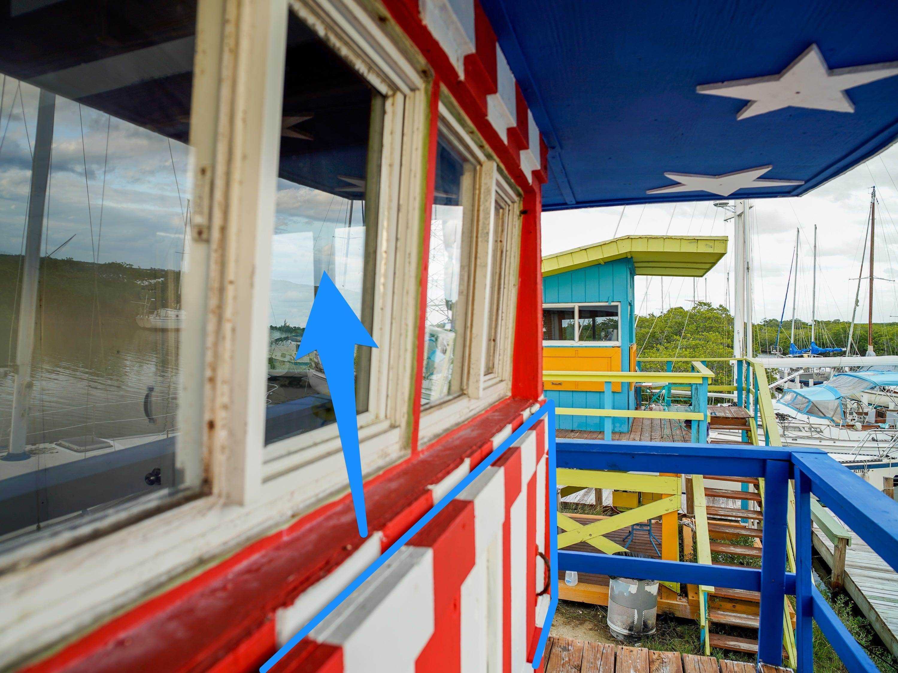 Ein blauer Pfeil zeigt von den Fensterläden des Turms bis zu den Fenstern.  An einem bewölkten Tag ist im Hintergrund ein weiterer Turm zu sehen