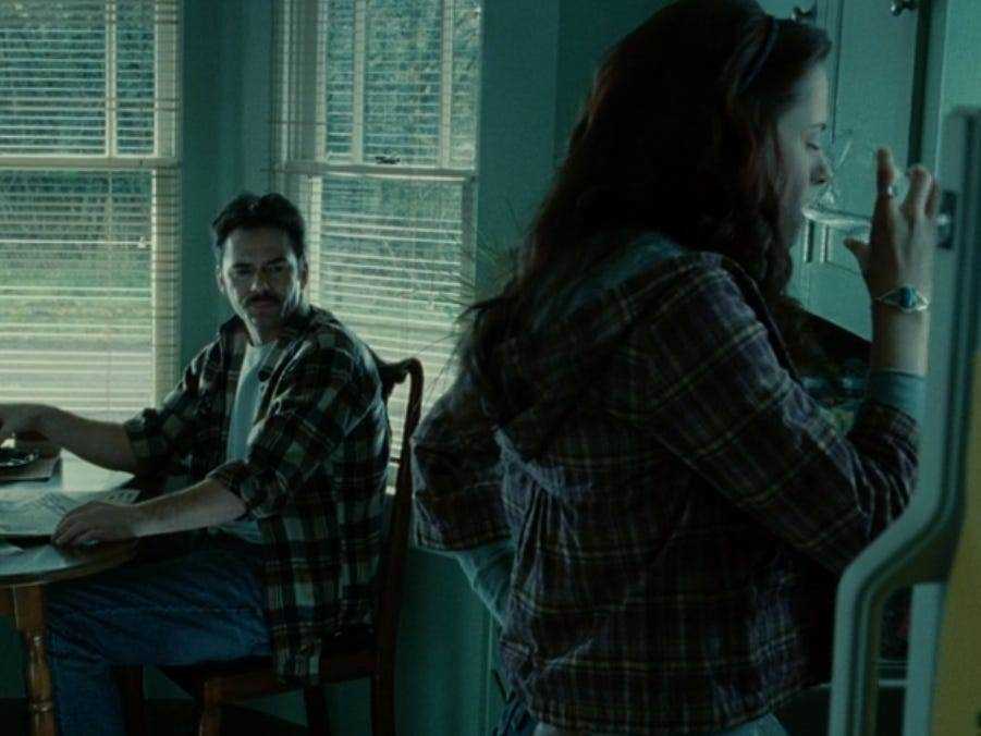 Bella trinkt Wasser, während Charlie in der Küche an einem Tisch am Fenster sitzt