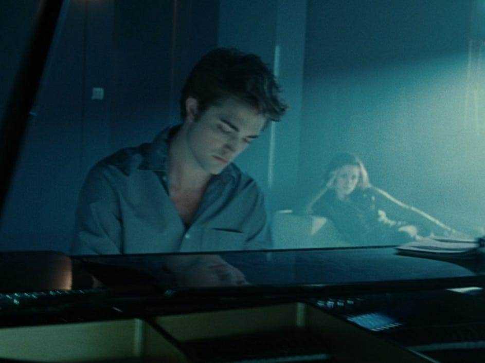 Edward spielt am Klavier, während Bella in der Dämmerung im Hintergrund sitzt und zuschaut