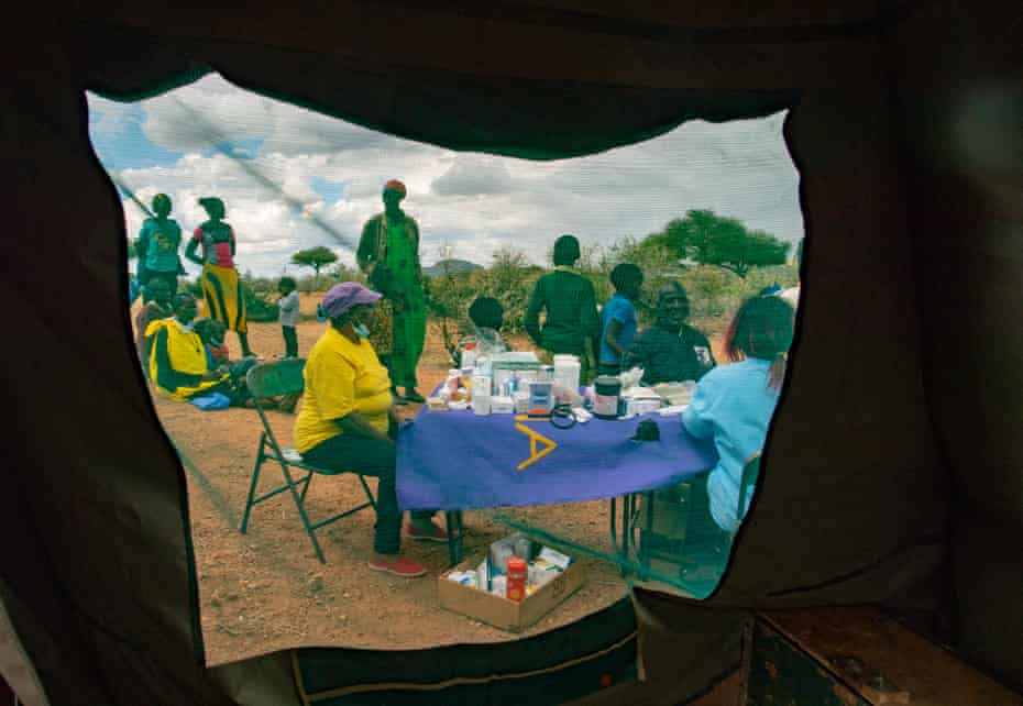 Als die Kamele ankommen, stellen Gesundheitspersonal Tische und Zelte für eine mobile Klinik auf.