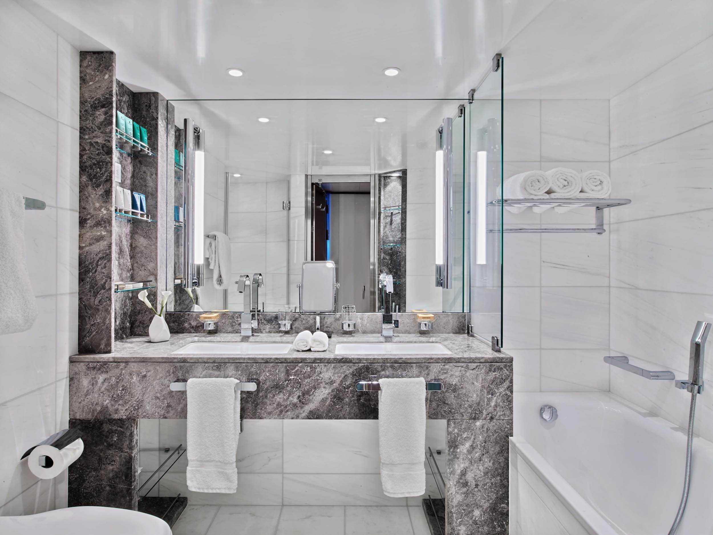 ein modernes Badezimmer in Weiß und Marmor mit Waschbecken und Badewanne
