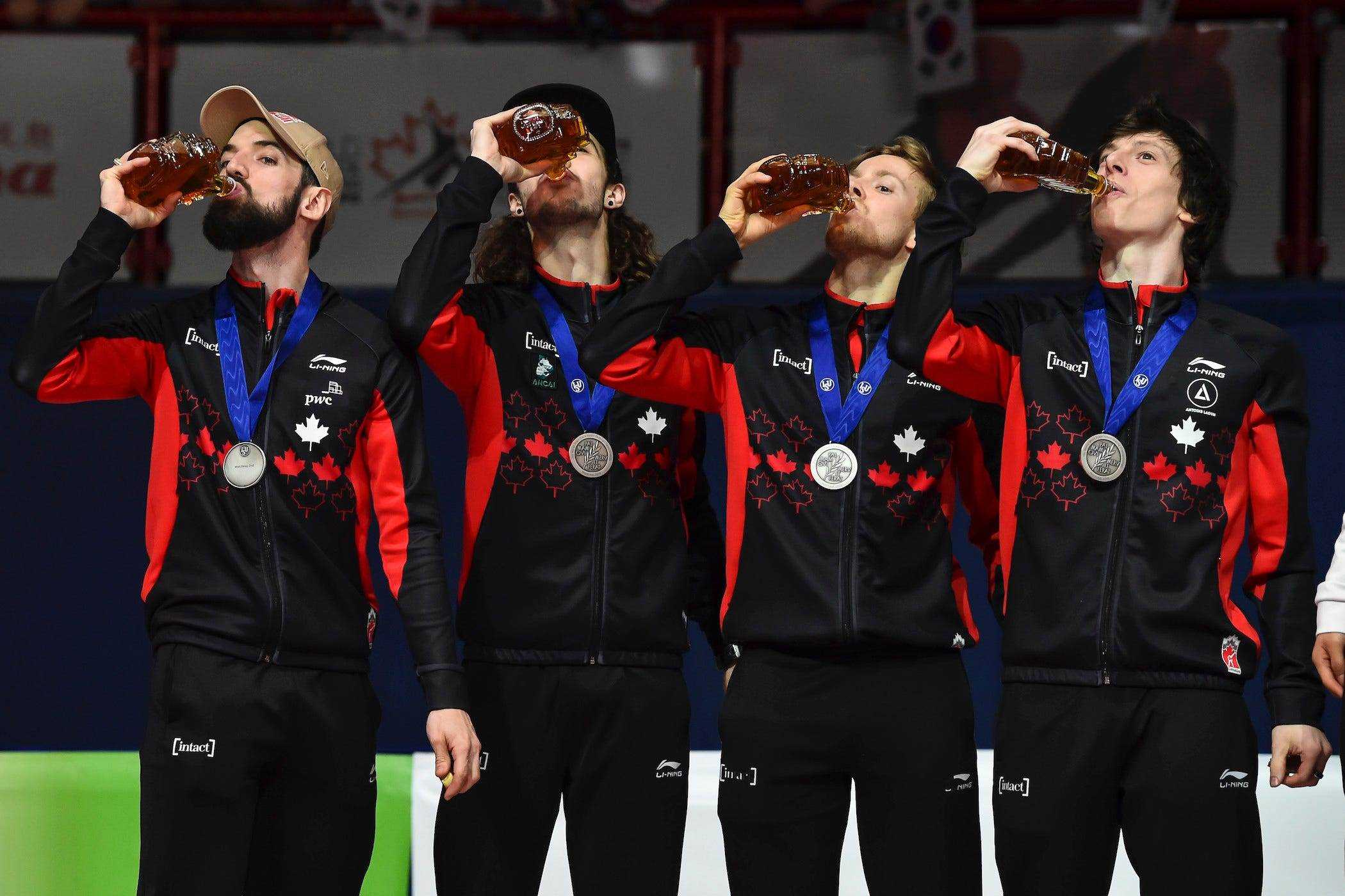 4 Mitglieder des Teams Kanada mit Medaillen auf, Ahornsirup trinken