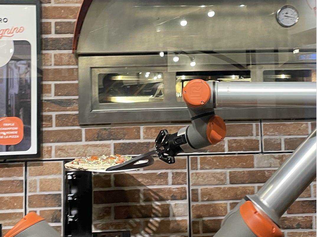 Der Roboterarm, der die Pizza hält, bewegt sie in den Ofen
