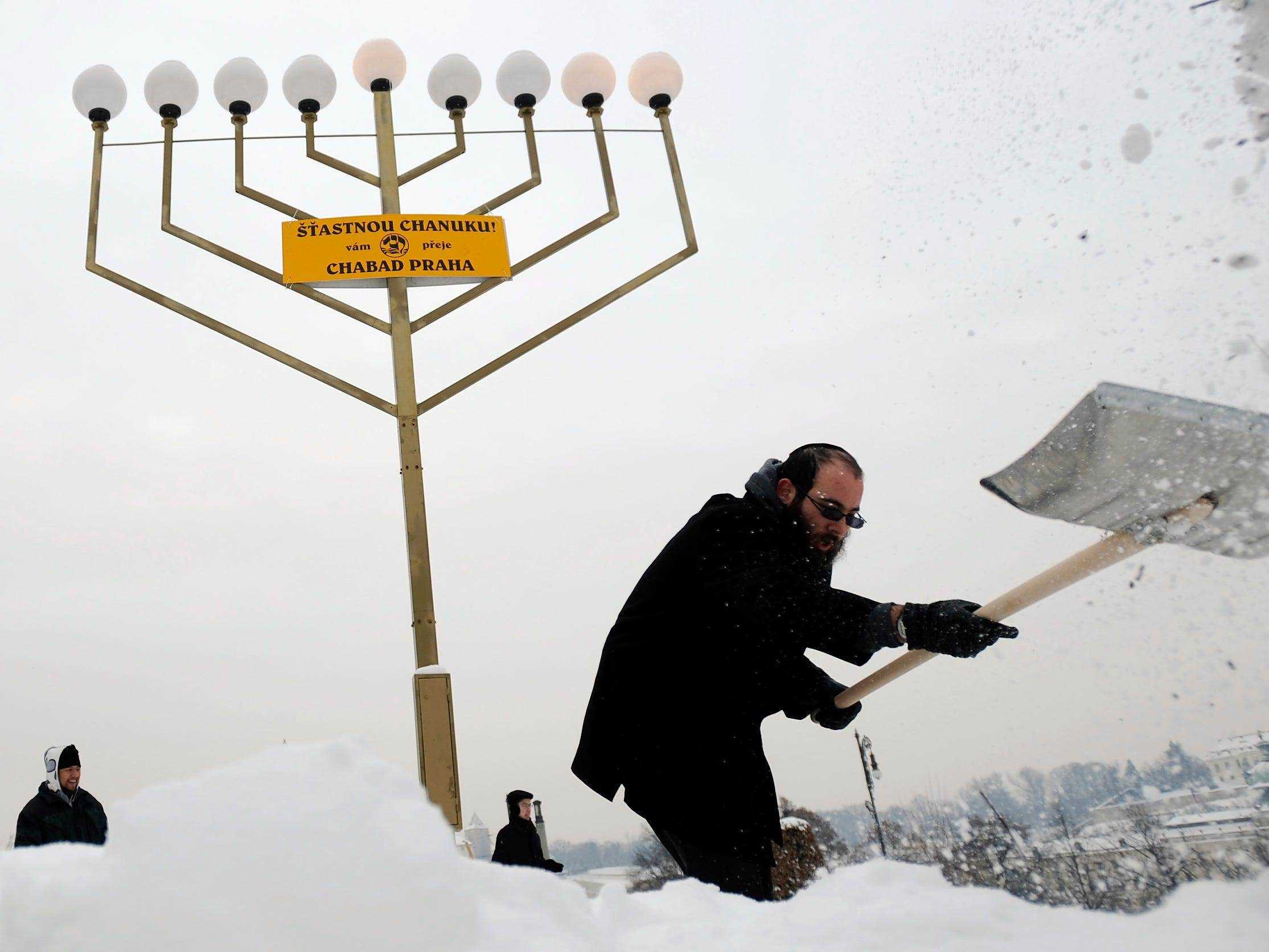 Yeshiva-Studenten räumen Schnee auf der Menora vor der Lichtzeremonie zum Beginn von Chanukka in Prag.