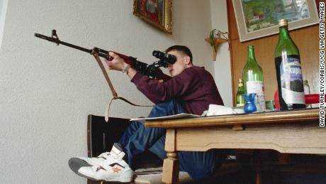 Ein bosnischer Scharfschütze versucht, während des Krieges in den 1990er Jahren von seiner Position im 20. Stock eines Gebäudes in Sarajevo aus serbische Scharfschützen in den Bergen zu erschießen.