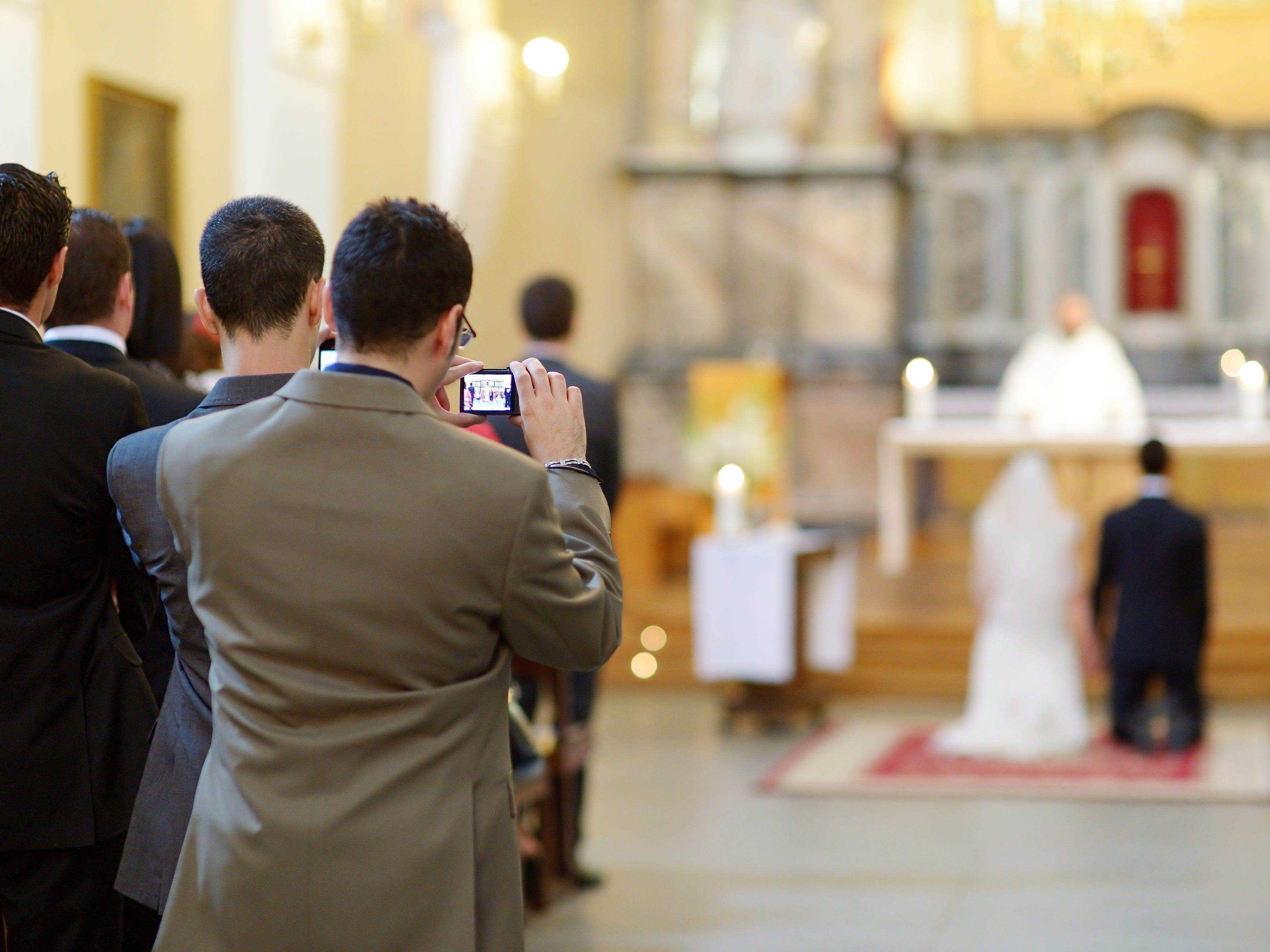 Gast, der bei einer Hochzeitszeremonie ein Foto oder Video macht