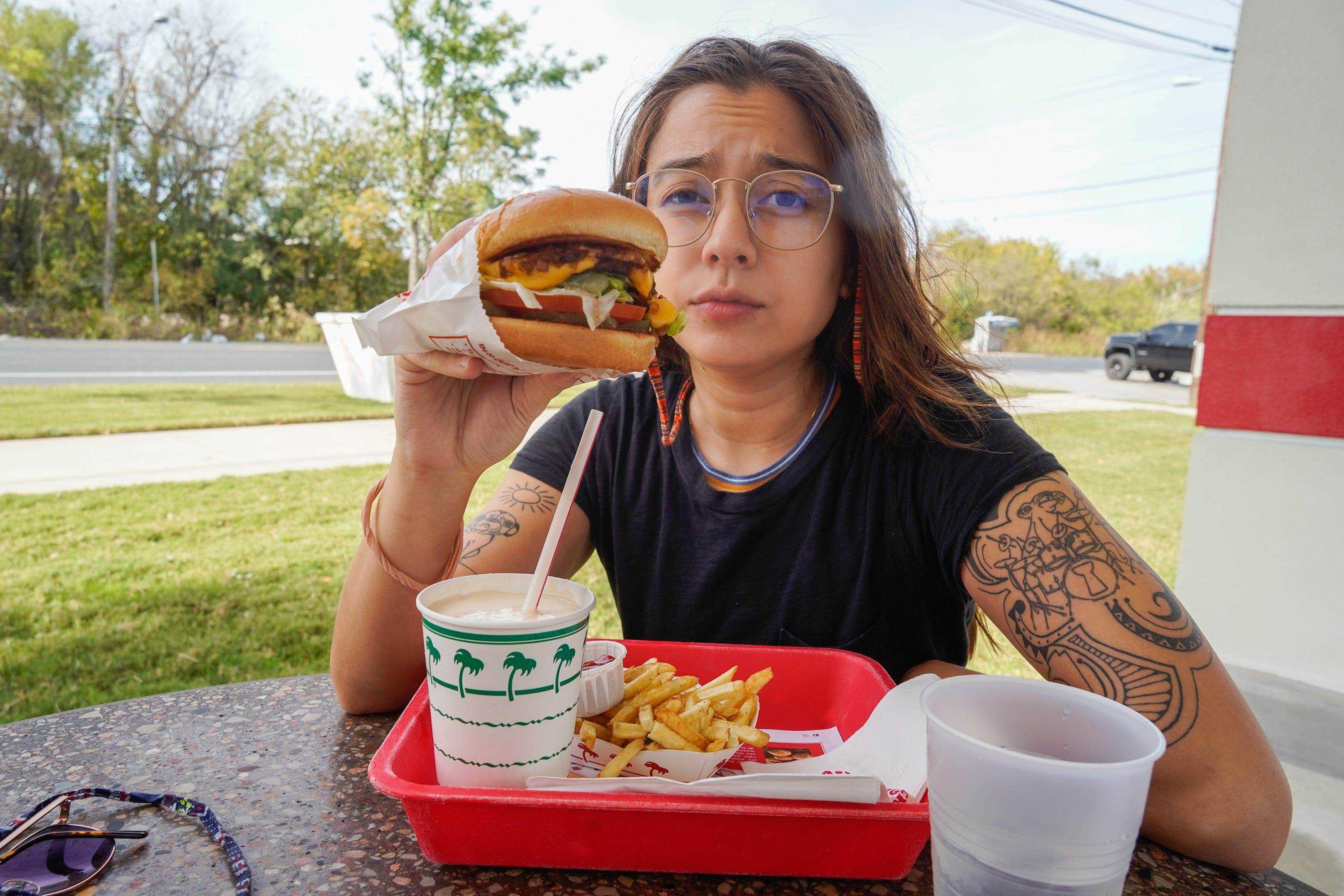 Die Autorin sitzt hinter ihrem In-N-Out-Essen, während sie den Burger in der Hand hält