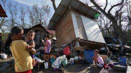 Einwohner stehen nach dem Taifun Rai in Talisay, Provinz Cebu, Zentralphilippinen am 18. Dezember 2021 vor beschädigten Häusern. 