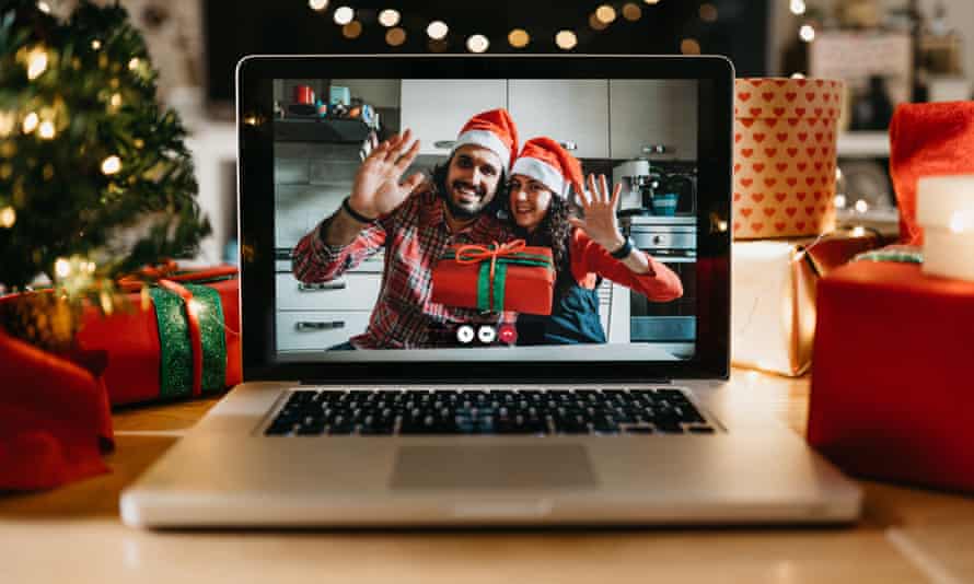 Ein Laptop auf einem Tisch, umgeben von Weihnachtsgeschenken, auf dem ein Video von zwei Personen mit Weihnachtsmützen zu sehen ist