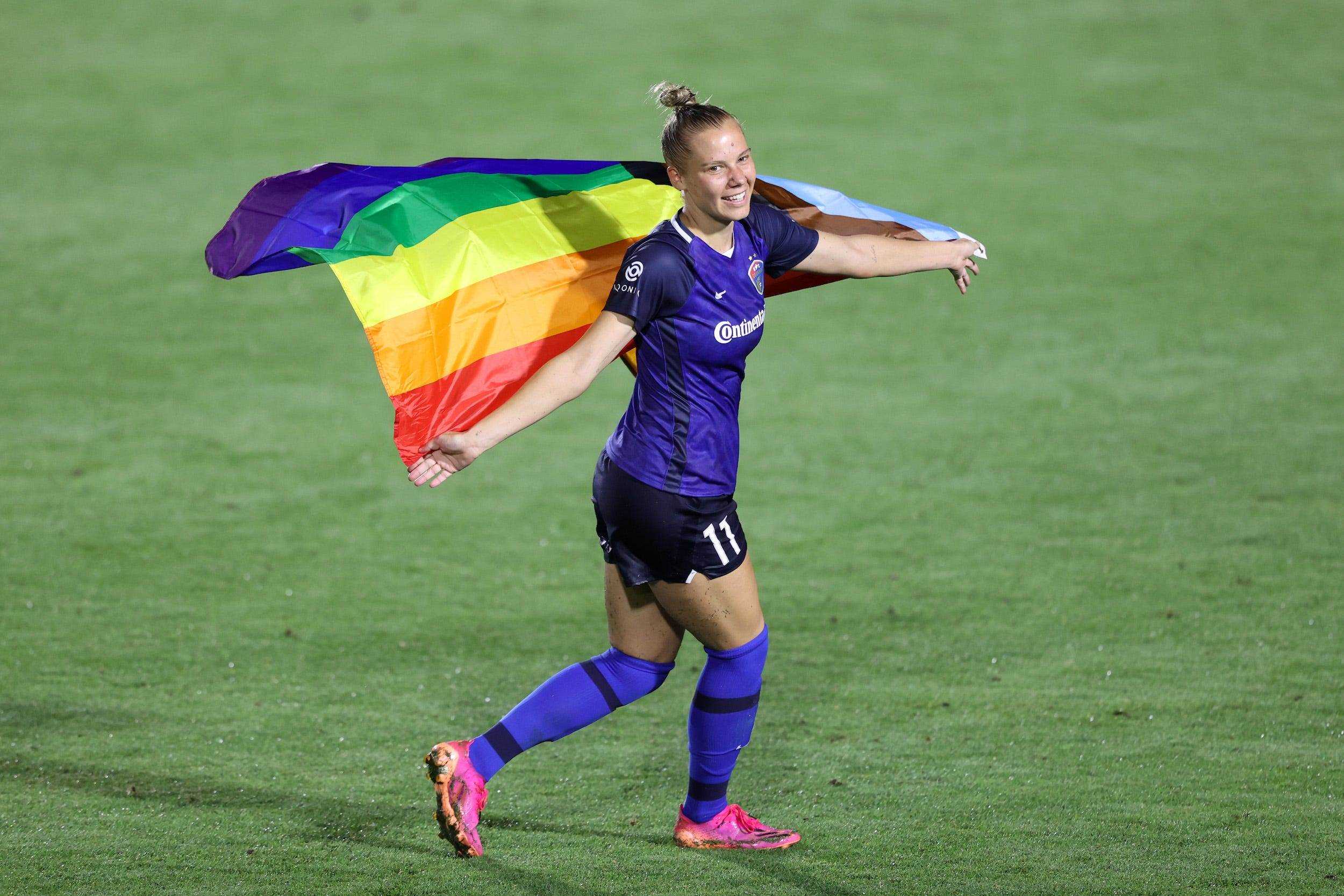 Der mutige Stürmer Merritt Mathias posiert mit einer Regenbogen-Pride-Flagge nach einem Spiel gegen die Portland Thorns in der Pride-Nacht 2021 in North Carolina.