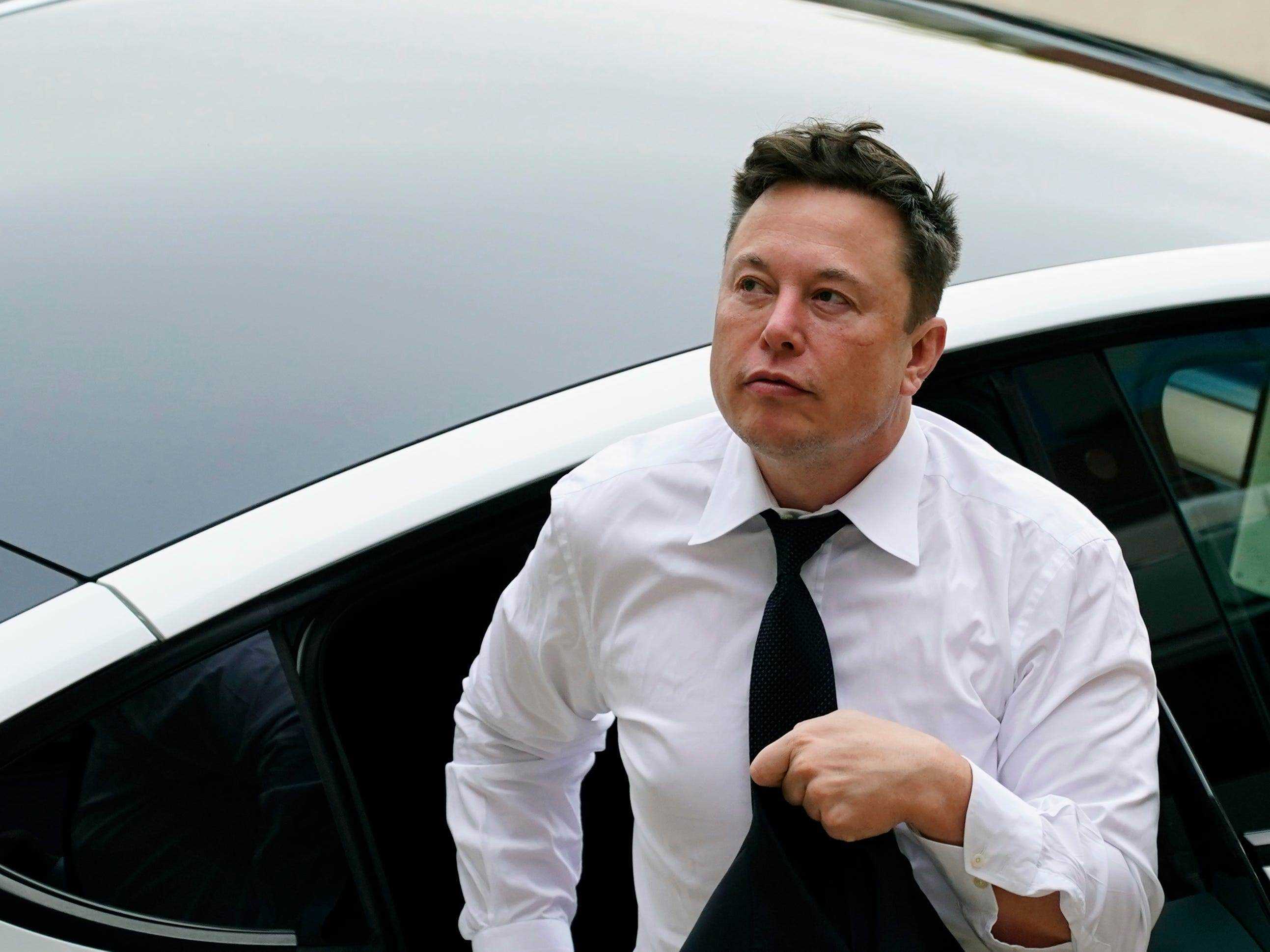 Tesla-Chef Elon Musk in weißem Hemd und Krawatte verlässt den Rücksitz eines weißen Tesla