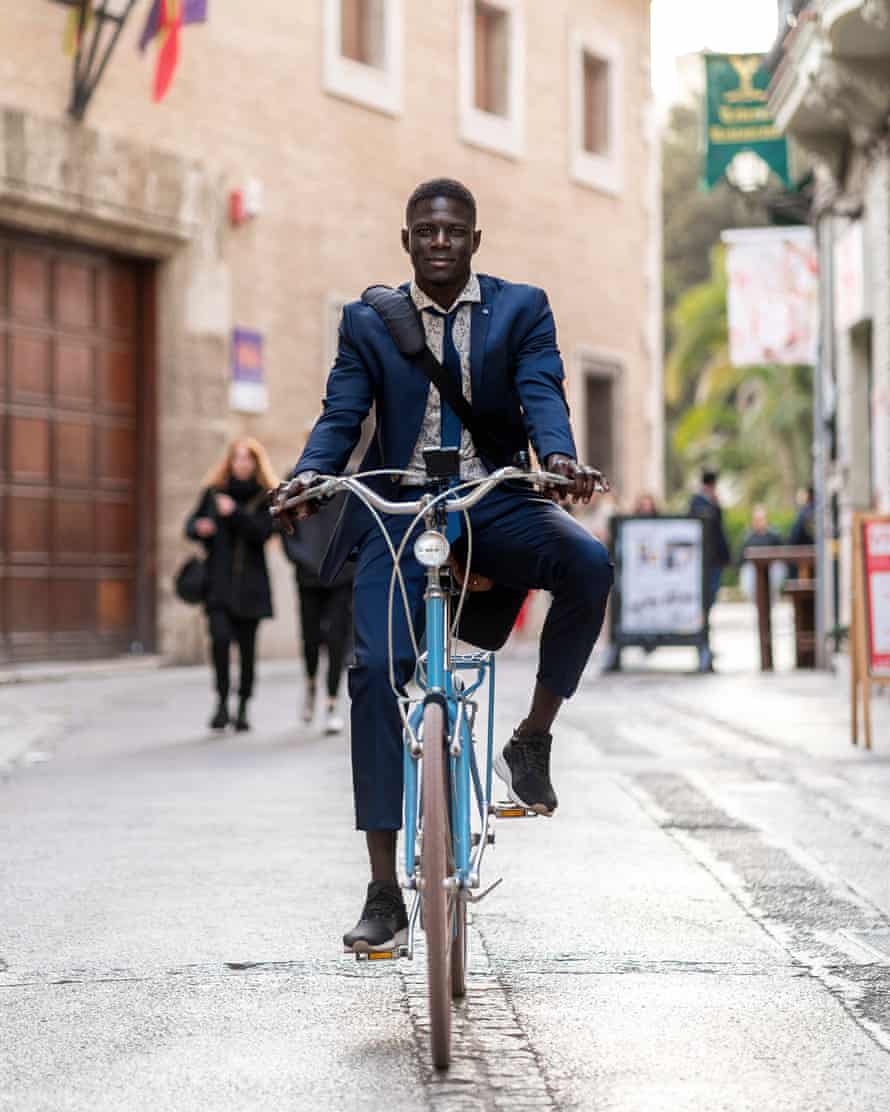 Porträt des jungen Geschäftsmannes, der Fahrrad in der Stadt fährt
