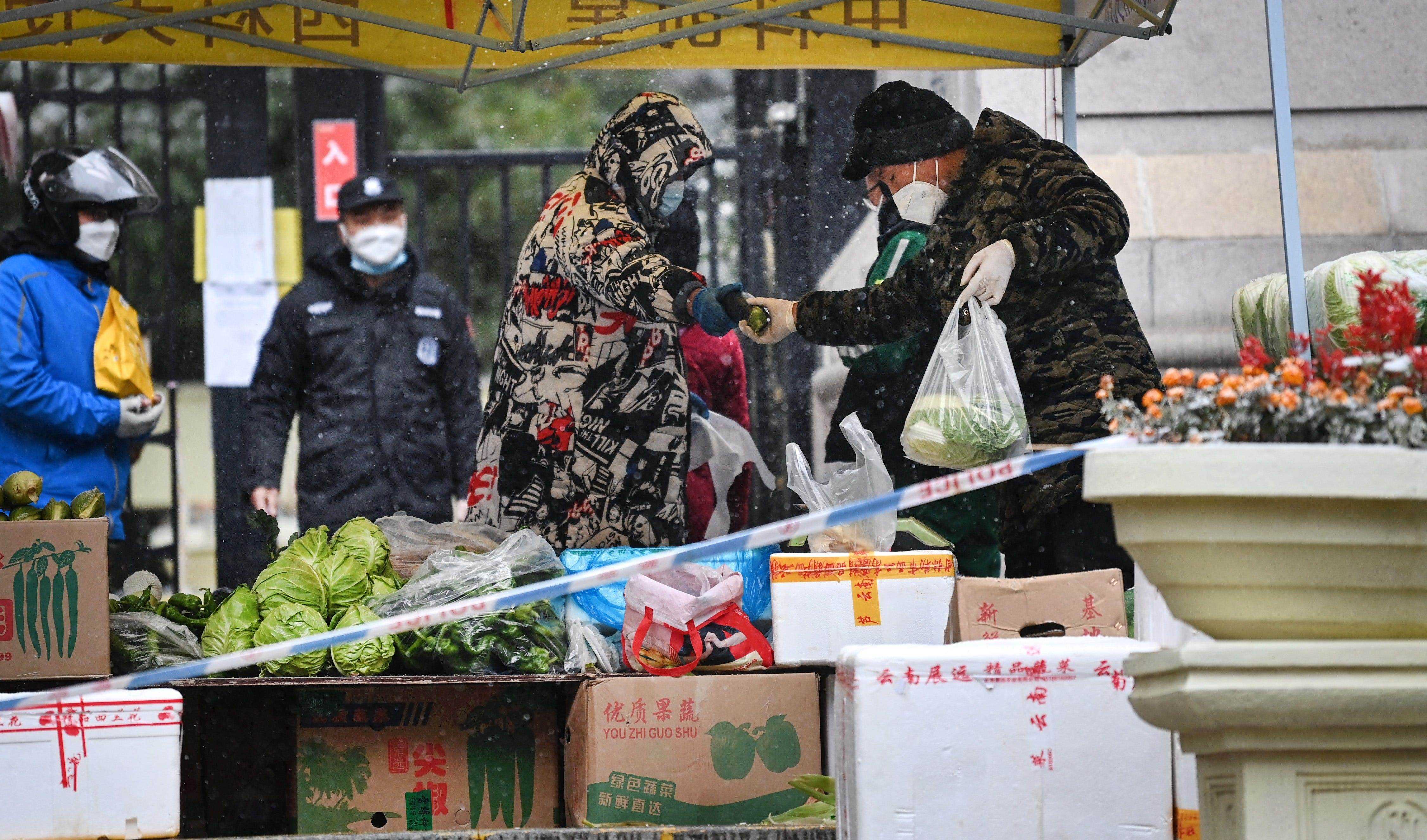 Am Eingang eines abgeschotteten Wohngebiets in Xi'an . entsteht ein Gemüsemarkt