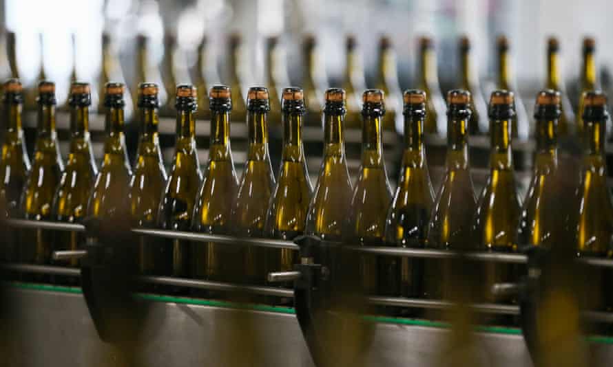 Eine Serie von Sektflaschen mit Korkverschluss, während der Produktion gesehen
