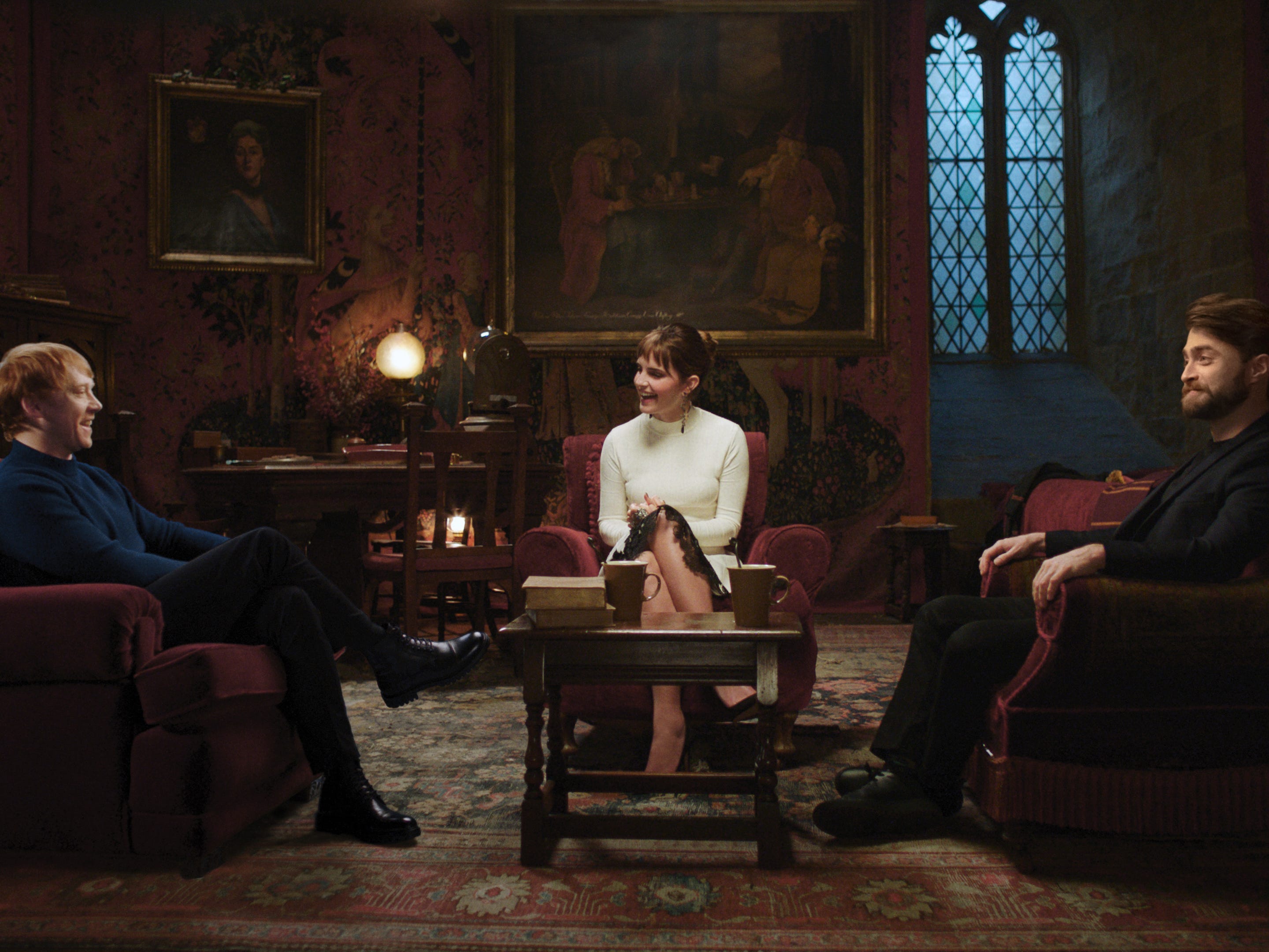 Rupert Grint, Emma, ​​Watson und Daniel Radcliffe sitzen zusammen im Gryffindor-Gemeinschaftsraum während des Harry Potter-Specials zum 20-jährigen Jubiläum