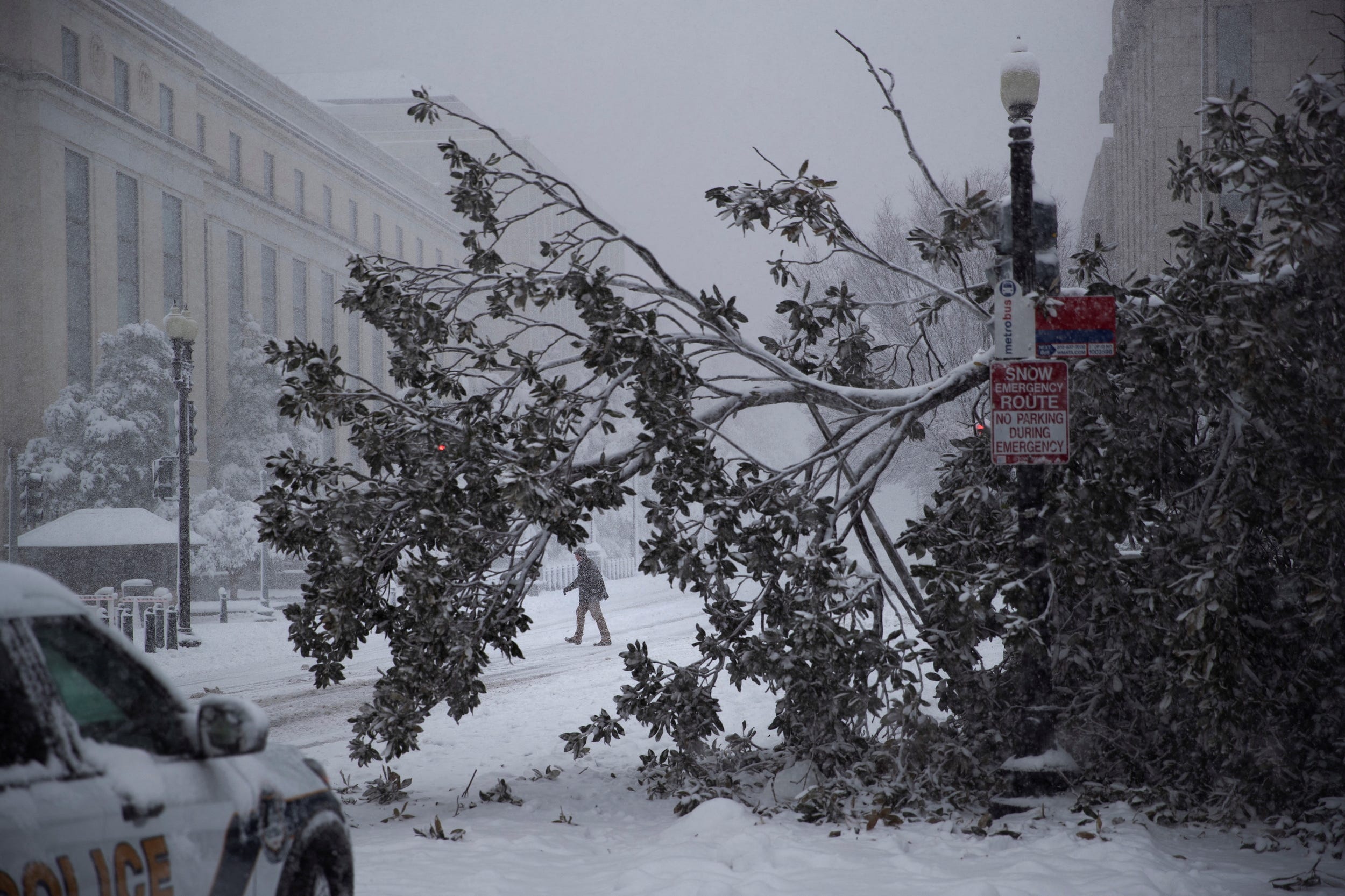 Ein Besucher überquert die Independence Avenue hinter einem umgestürzten Baum inmitten eines Schneesturms vor dem Dirksen Senate Office Building auf dem Capitol Hill in Washington, USA, 3. Januar 2022.