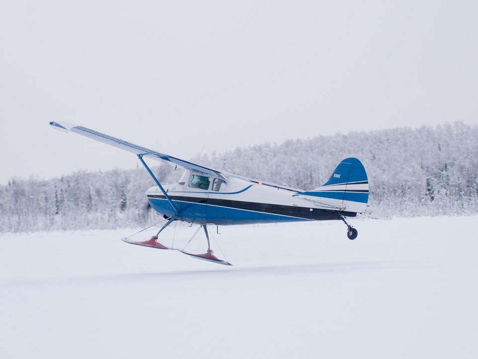 Bush-Flugzeug, das von einem zugefrorenen See in Alaska abhebt.