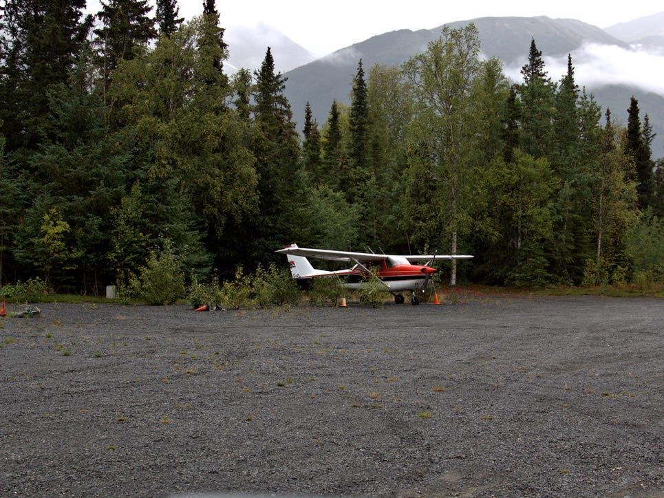 Buschflugzeug auf Schotterpiste geparkt.
