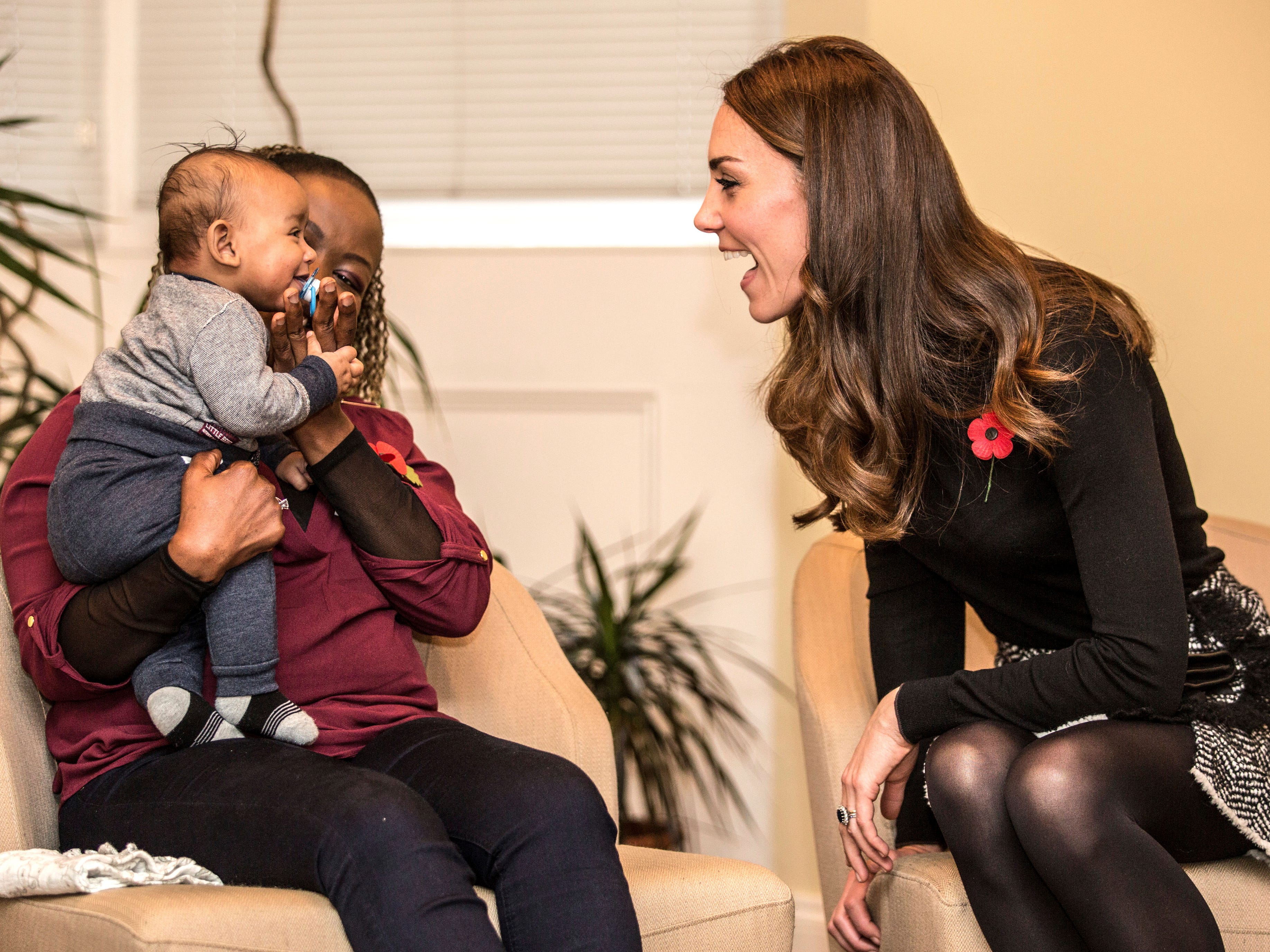 Kate Middleton plaudert mit einer anderen Mutter und lächelt ein Baby an.