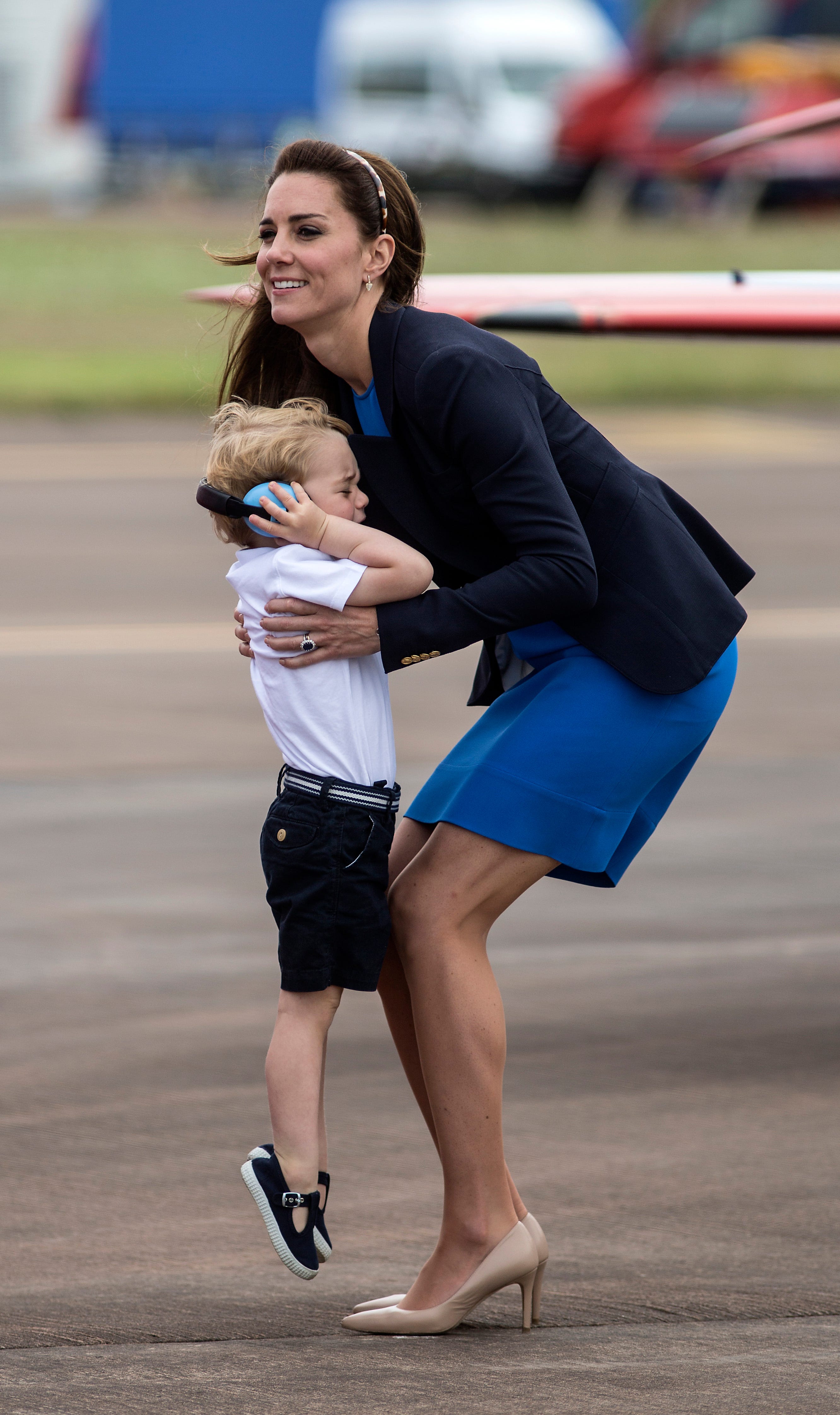Kate Middleton holt Prinz George ab, der sich mit Kopfhörern die Ohren zuhält.