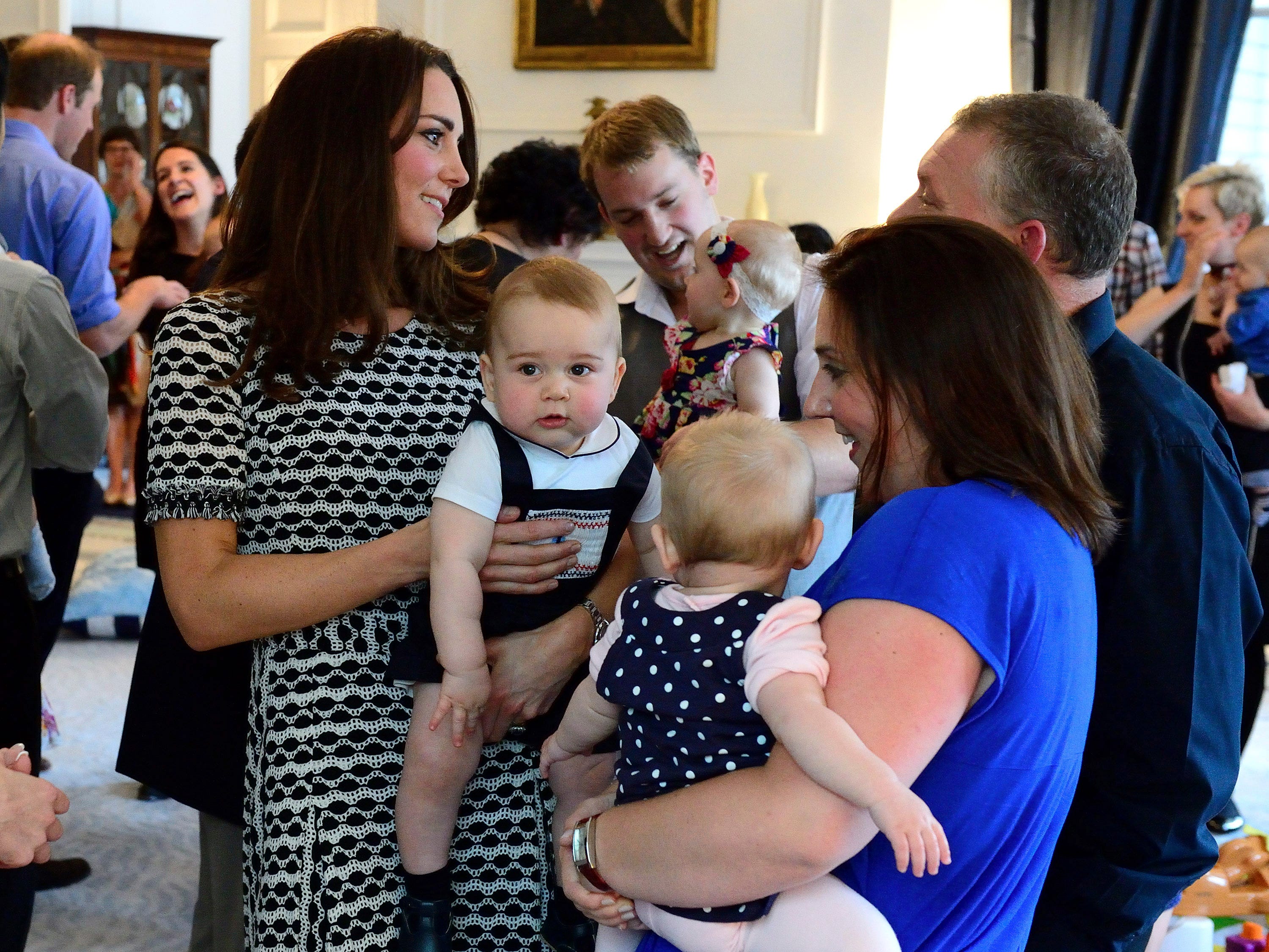 Kate Middleton hält Prinz George und spricht 2014 mit anderen Müttern.
