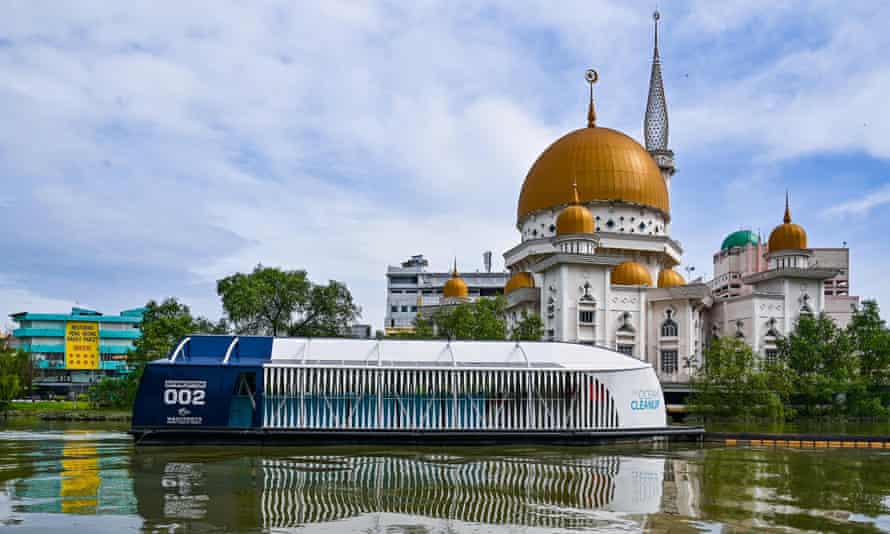 Ein Lastkahn bewegt sich entlang eines Flusses mit der Kuppel einer Moschee im Hintergrund