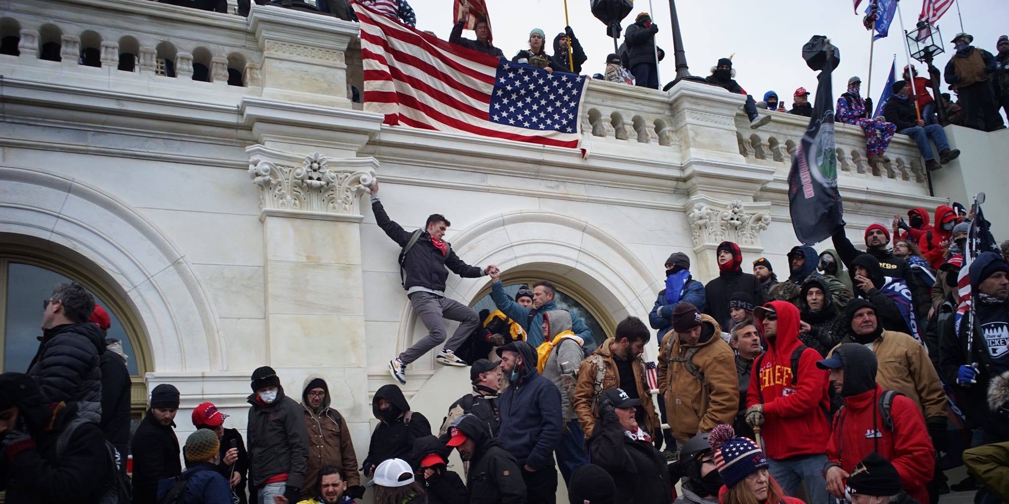 Jemand hängt unter einer amerikanischen Flagge an der Fassade des Kapitols.