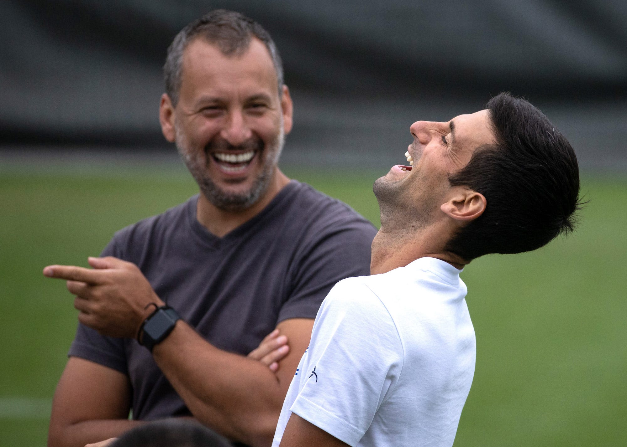 Der Serbe Novak Djokovic lacht während einer Trainingseinheit mit einem Mitglied des Trainerteams