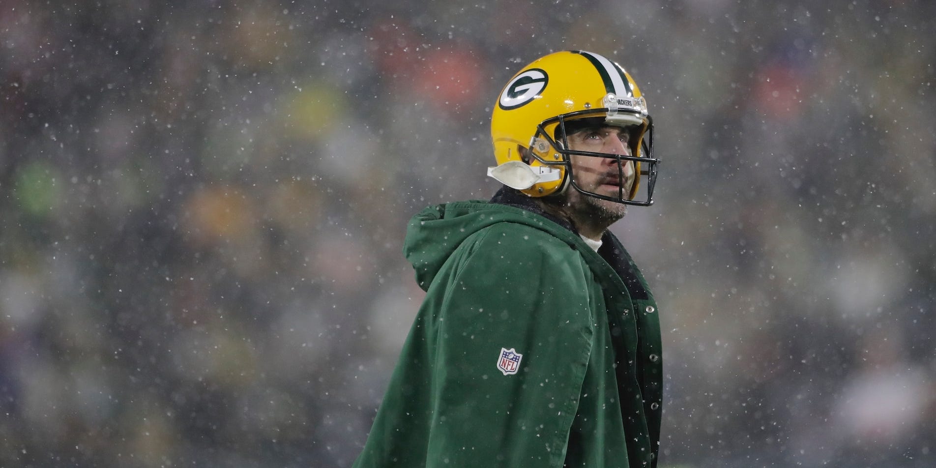 Aaron Rodgers blickt auf, als während des Playoff-Spiels der Packers gegen die 49ers im Jahr 2022 Schnee fällt.