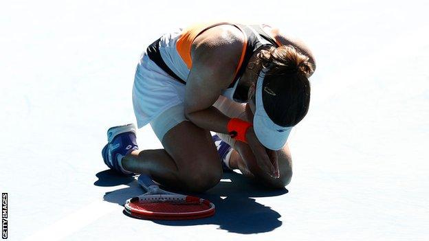Alize Cornet sinkt auf die Knie und hält ihre Hände zusammen, nachdem sie Simona Halep geschlagen hat