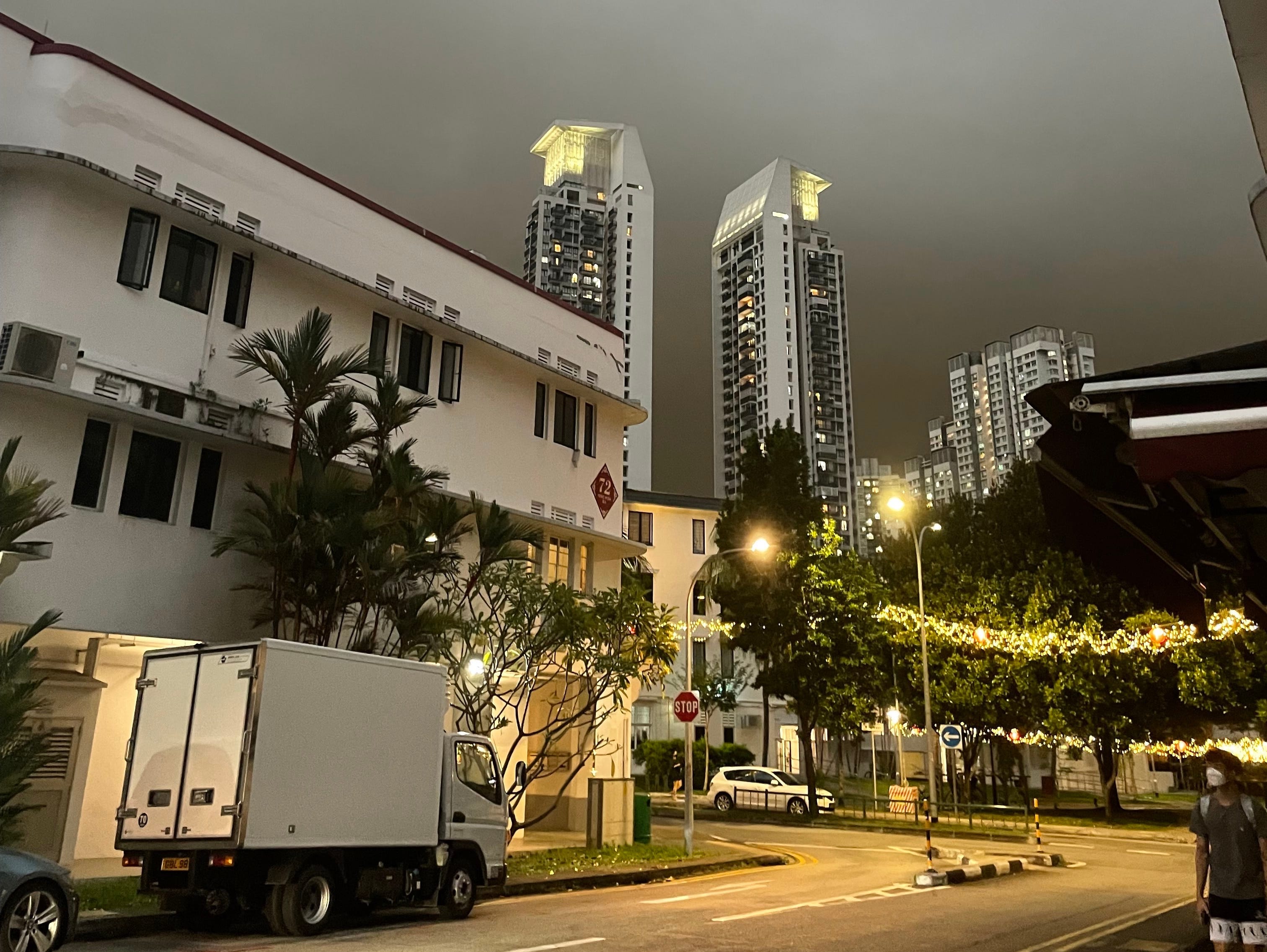Eine stürmische Nacht in Singapur mit Hochhäusern in der Ferne und einer leeren Straße