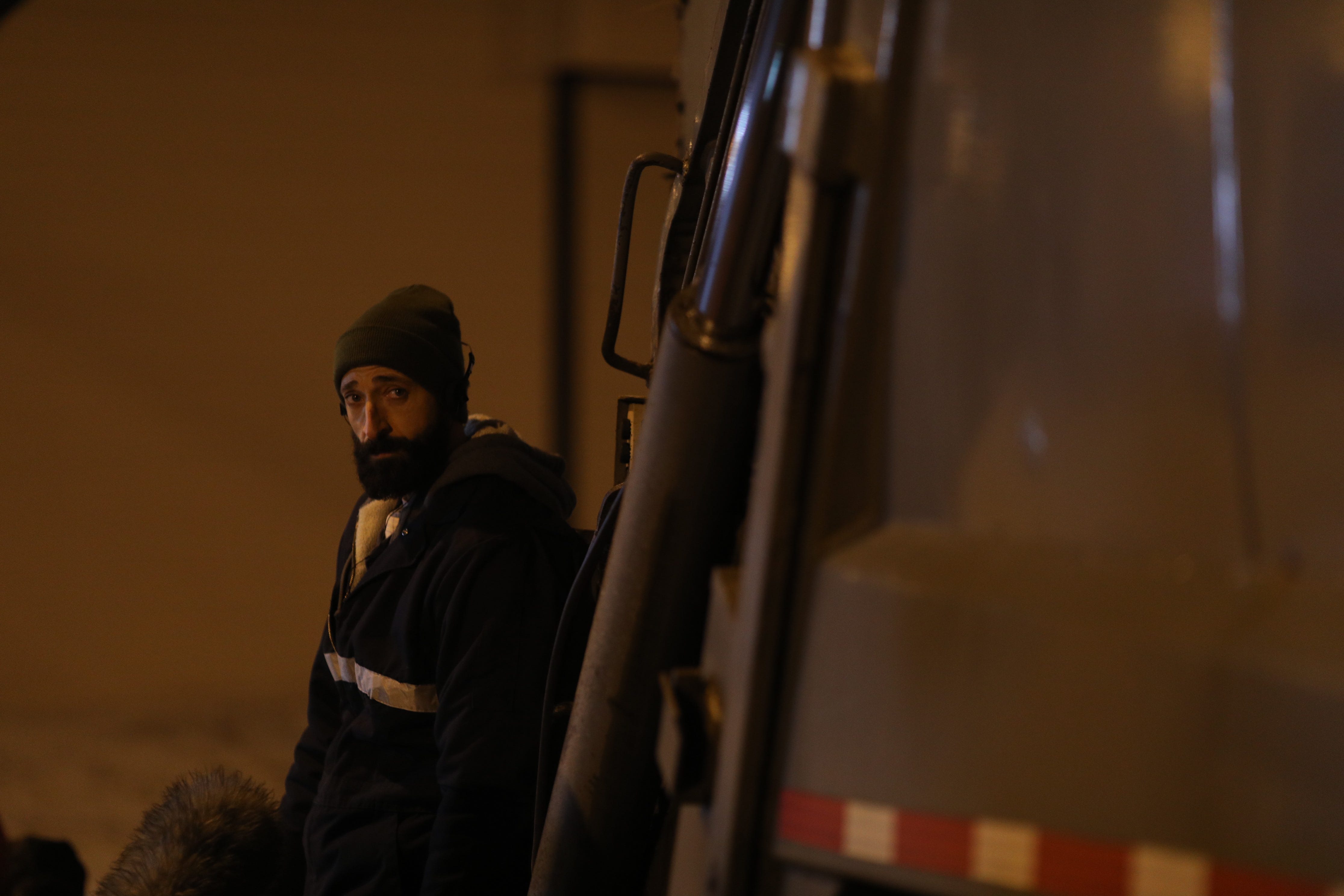 Adrien Brody steht neben einem Müllwagen